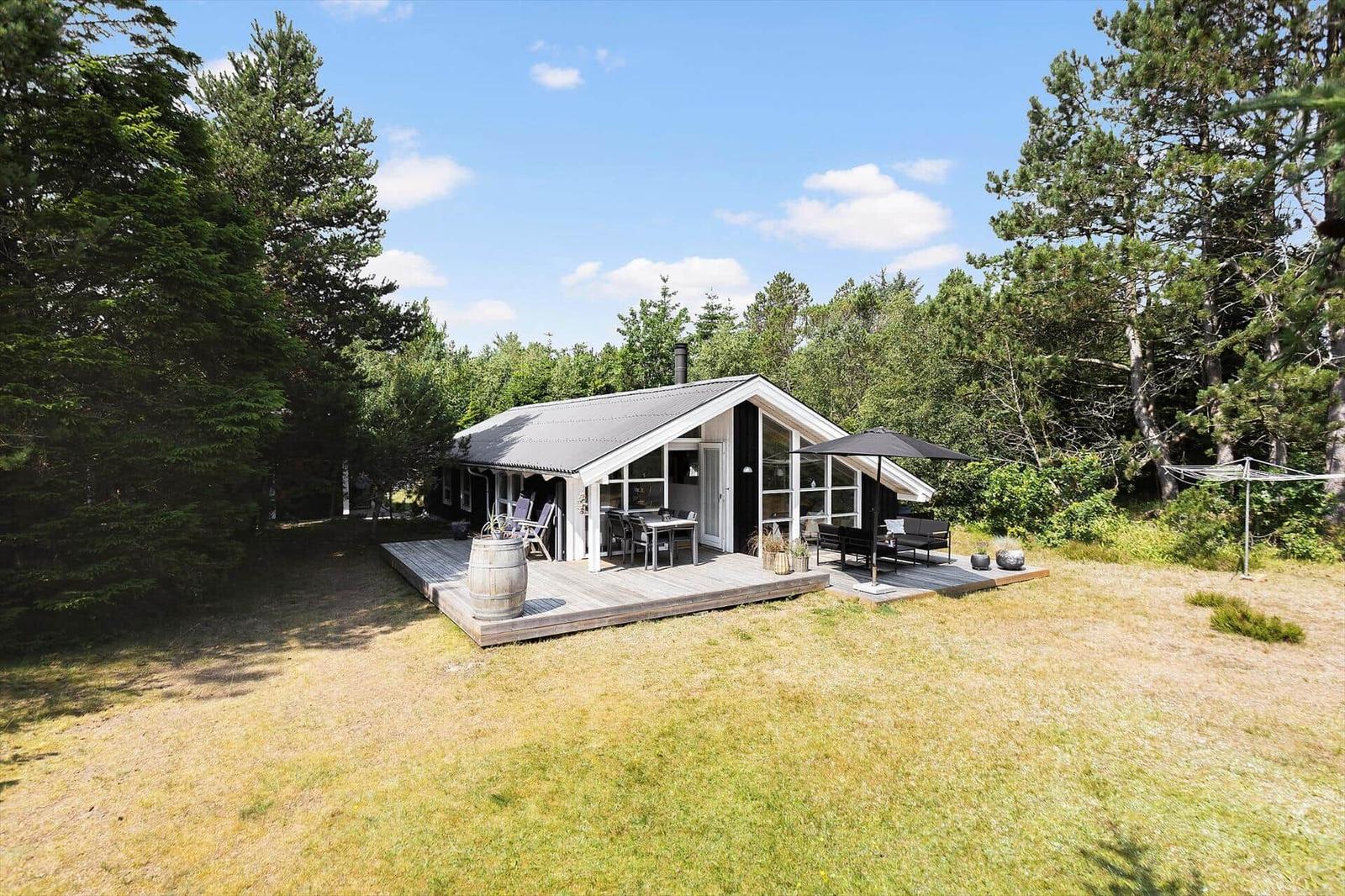Modern cabin with terrace, garden, surrounded by trees.