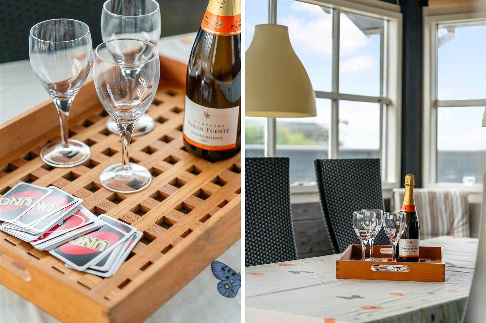 Ein Holztablett mit Champagner, Gläsern und Uno-Karten auf einem Tisch.