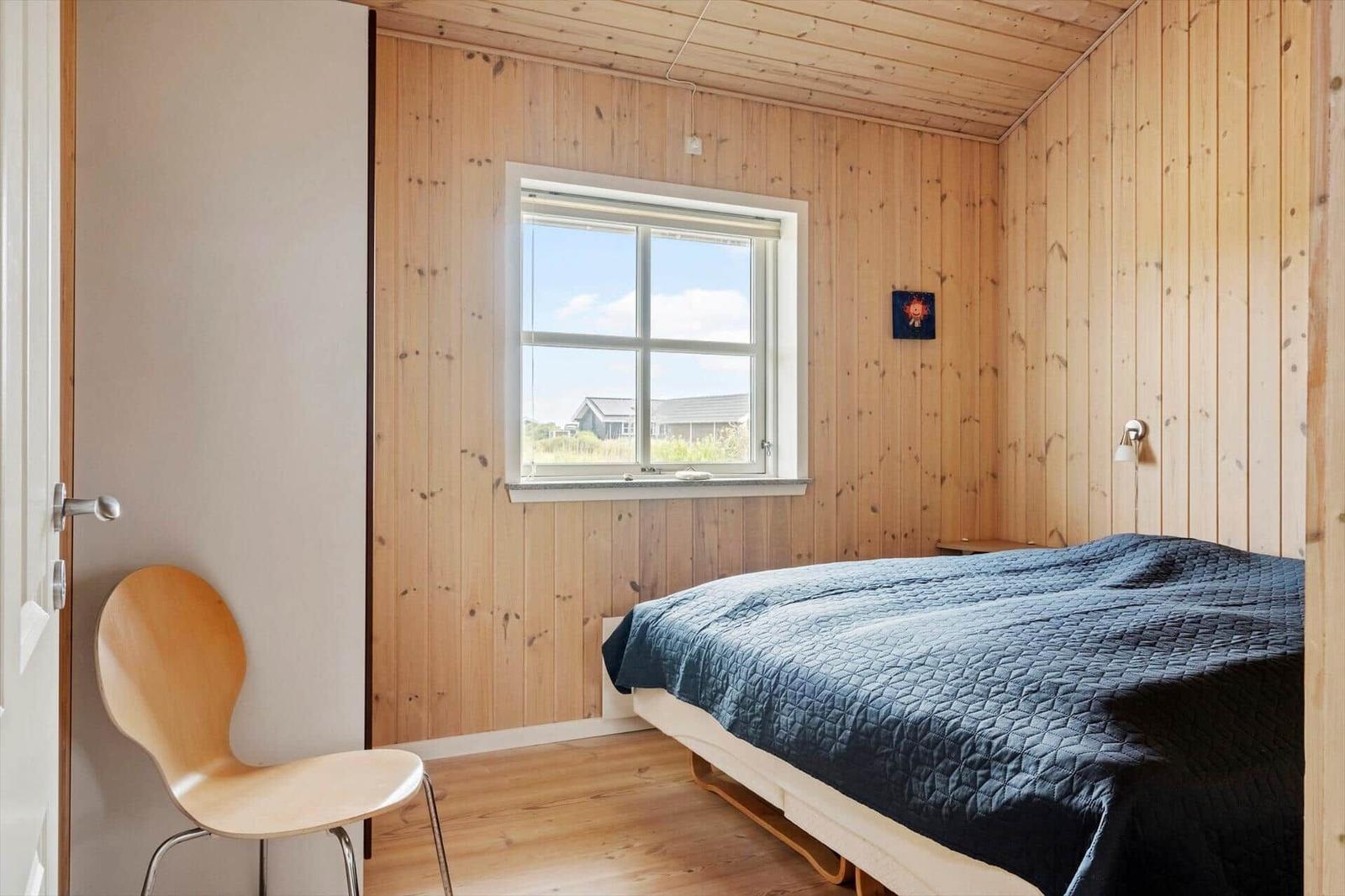 Ein Schlafzimmer mit Holzwänden, einem Bett und einem Fenster.