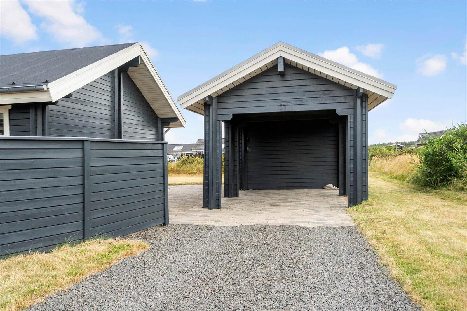 Einfahrt zu einem Haus mit Garage und Holzwand