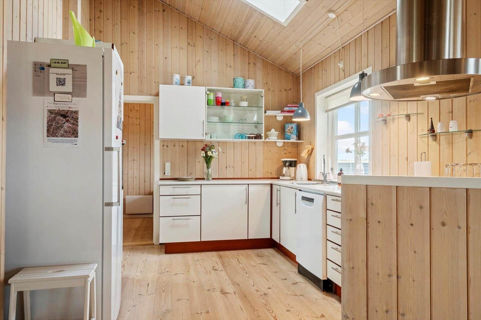 Küche mit Holzwänden, weißer Einbauküche und Fenster mit Blick.