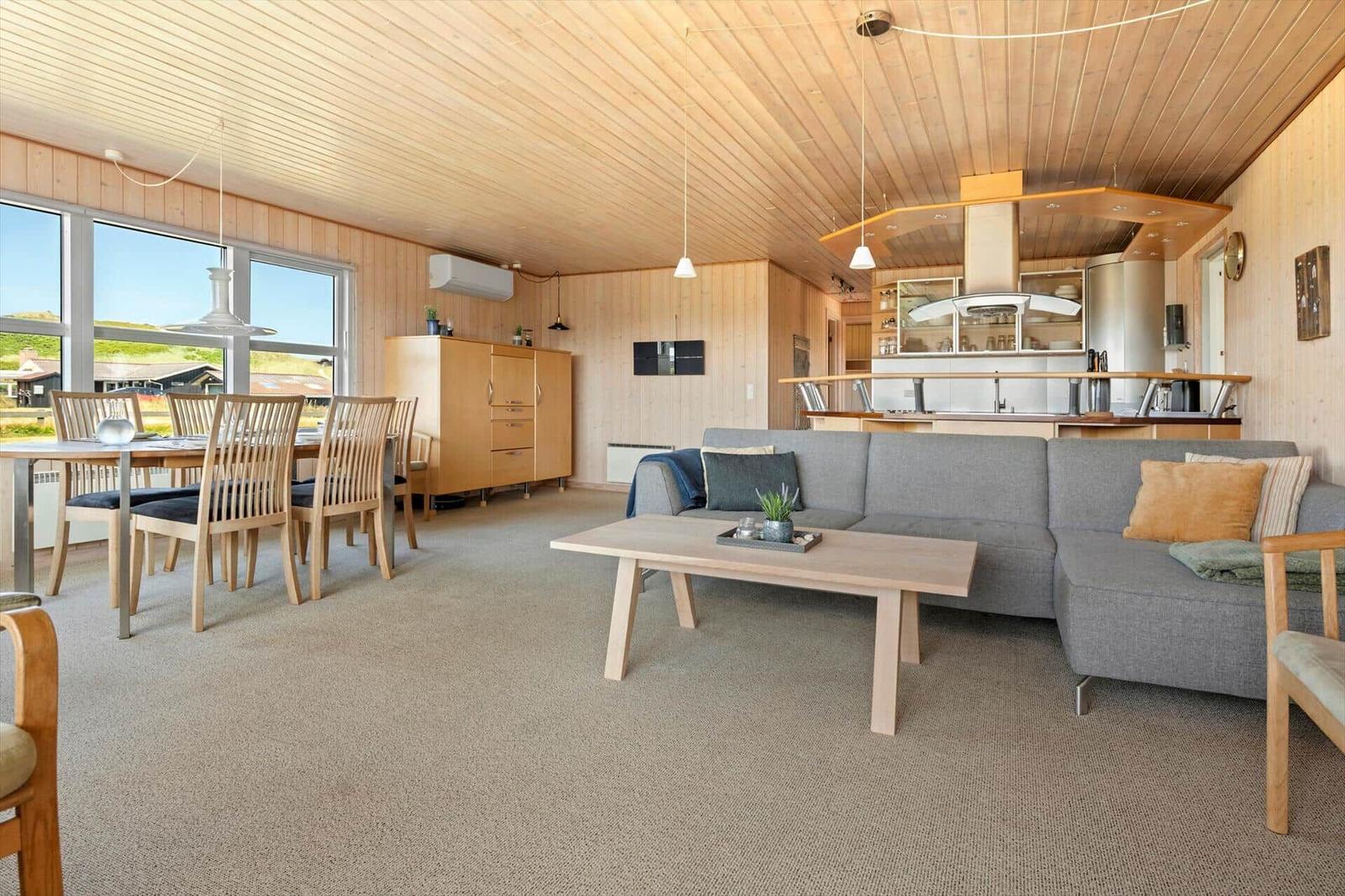 Wohn- und Essbereich mit Holzwand, Sofa und Küchenbereich.