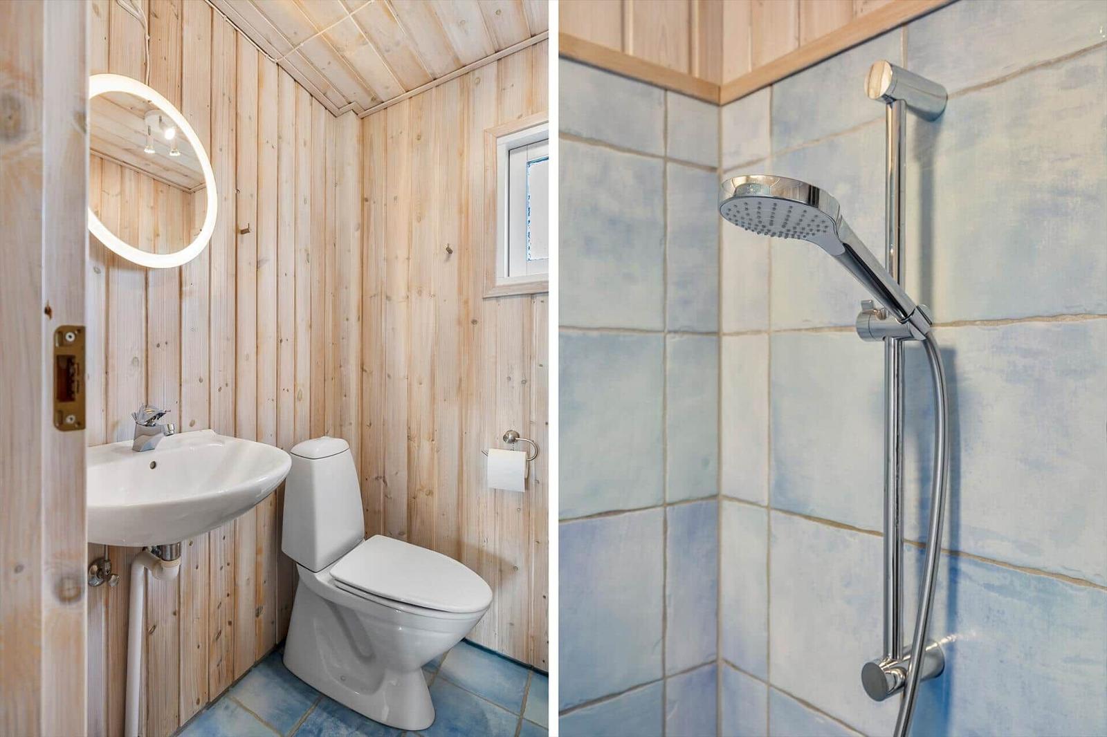 Bathroom with toilet, sink, and mirror. Shower with showerhead and tiles.