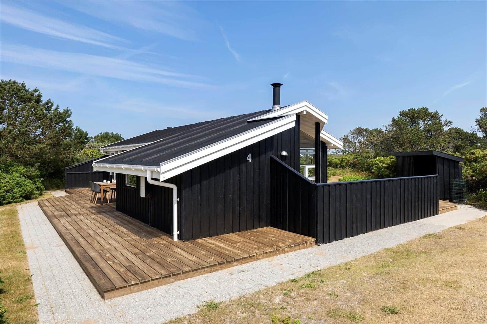 Black wooden cabin with terrace and garden. House number 4. Modern design with white accents.