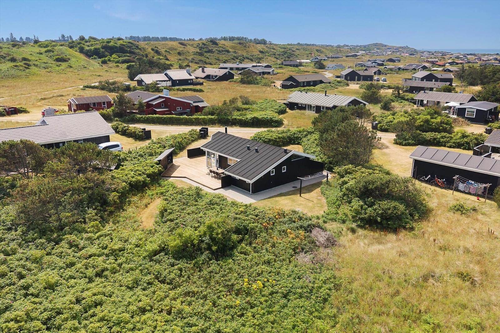 Modern house with terrace in green surroundings, view of coastal landscape.