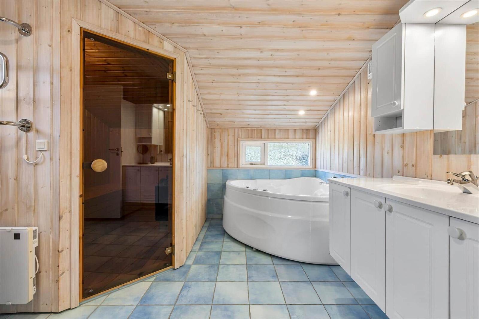 Bathroom with whirlpool, shower, and sauna. Wooden walls and blue tiled floor.