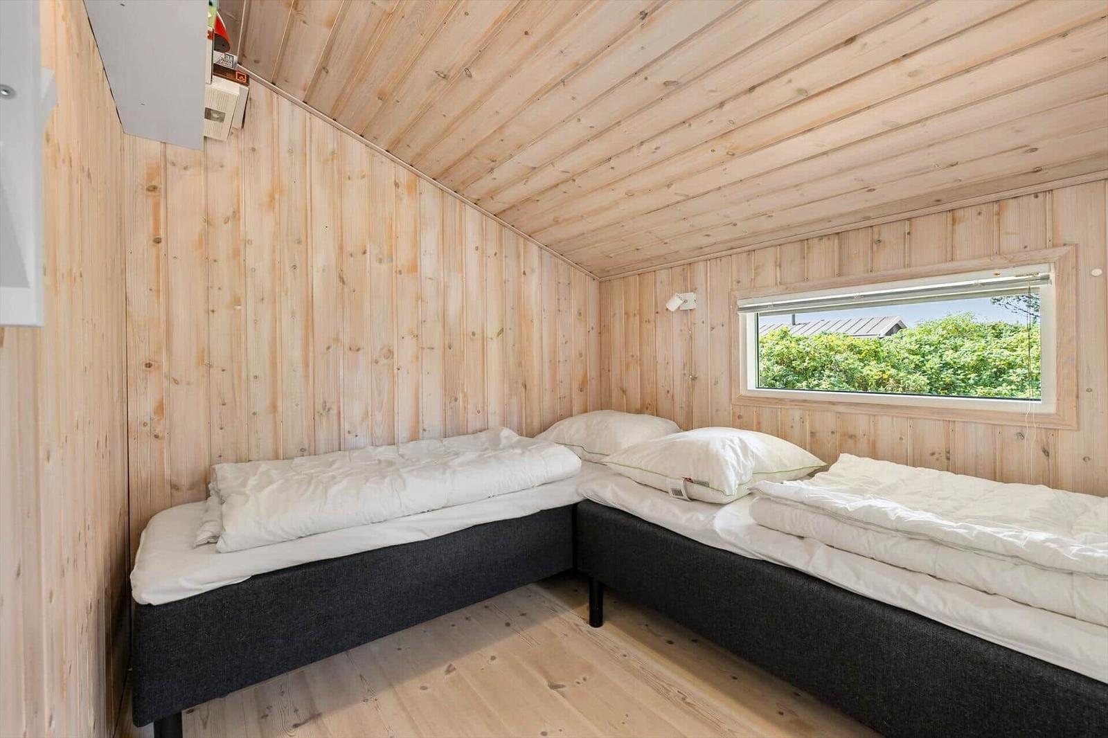Two single beds in a wooden house with window and attic.