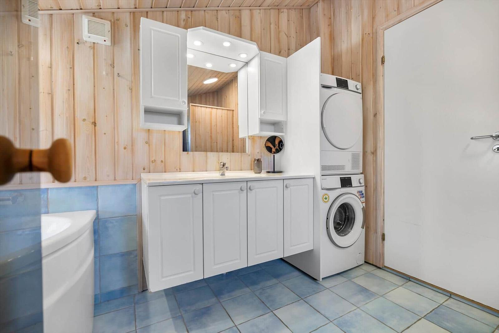 Bathroom with washing machine and dryer, wood wall and blue tiles
