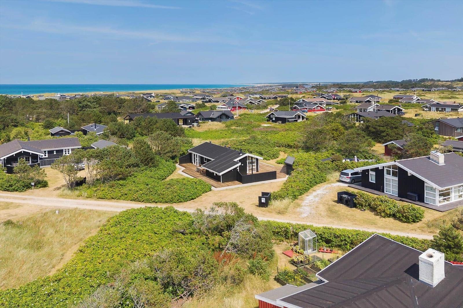 Overview of vacation homes near the beach with green vegetation and blue sea in the background.