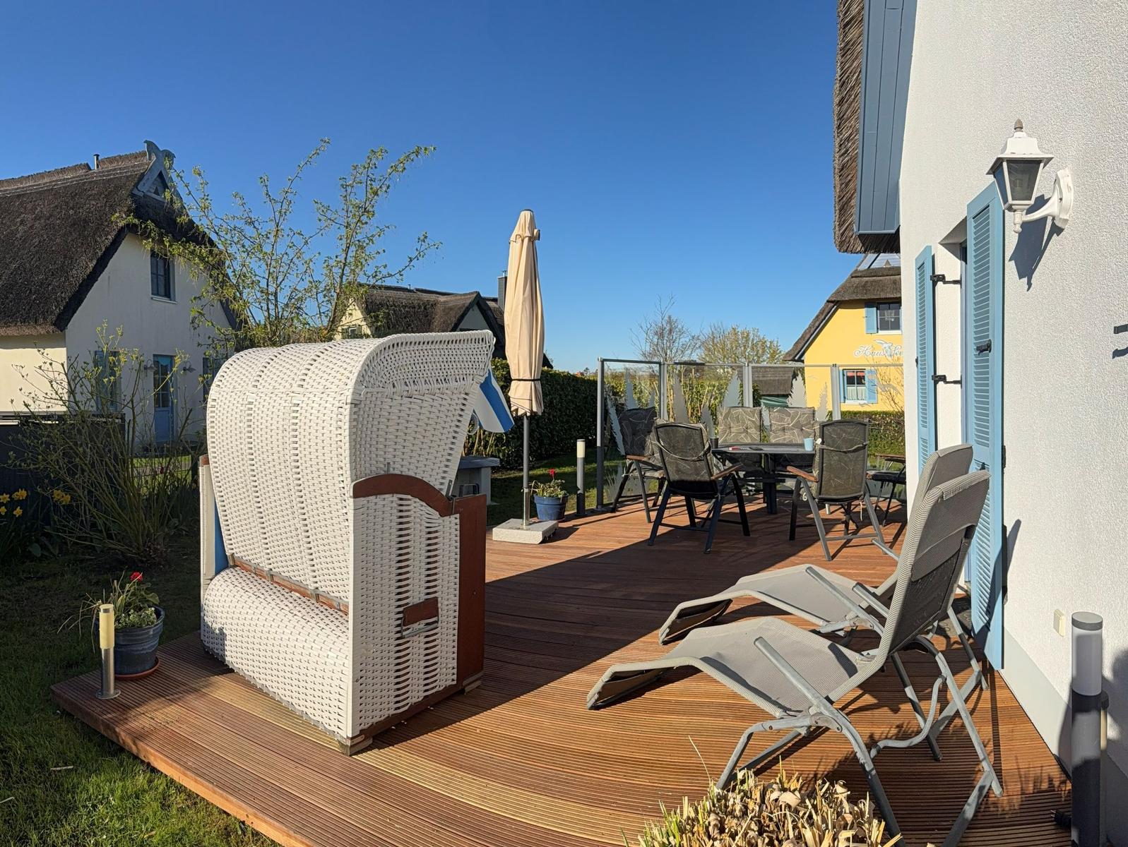 windgeschützte große Holz-Terrasse mit Grill, Sonnenschirm, 2 Relaxliegen, Tisch mit 6 Stühle und Auflagen, *Strandkorb (*von April-Oktober)