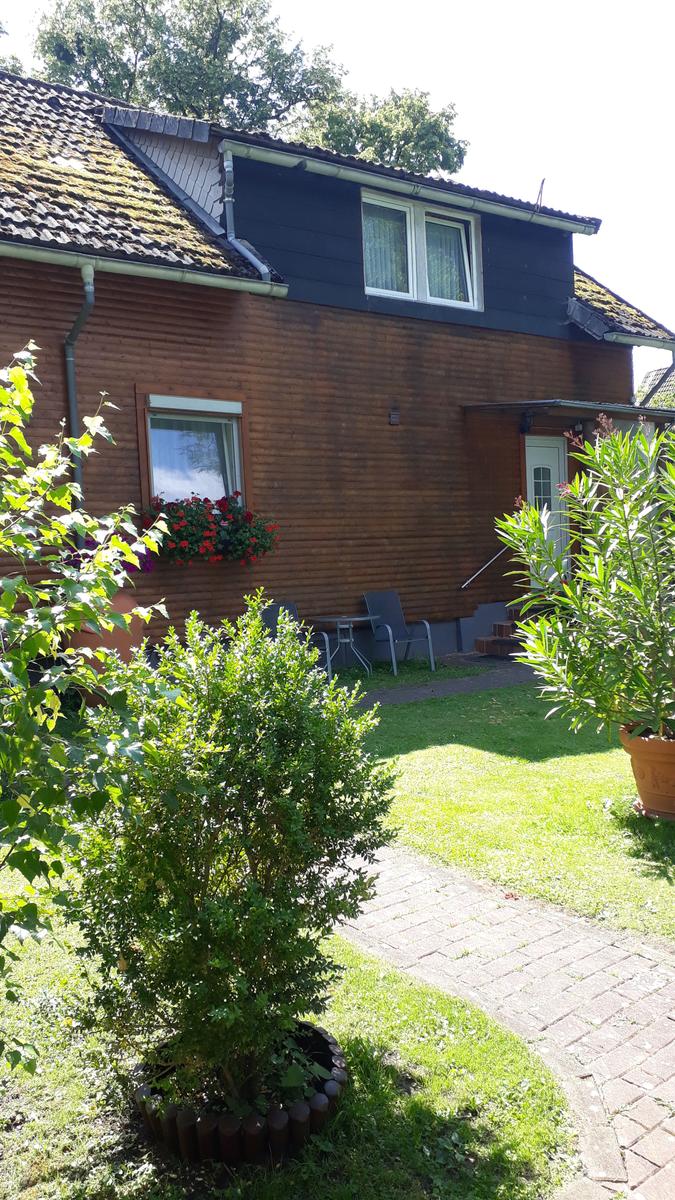 Haus mit Holzfassade, Garten und Terrasse mit Sitzgelegenheit.