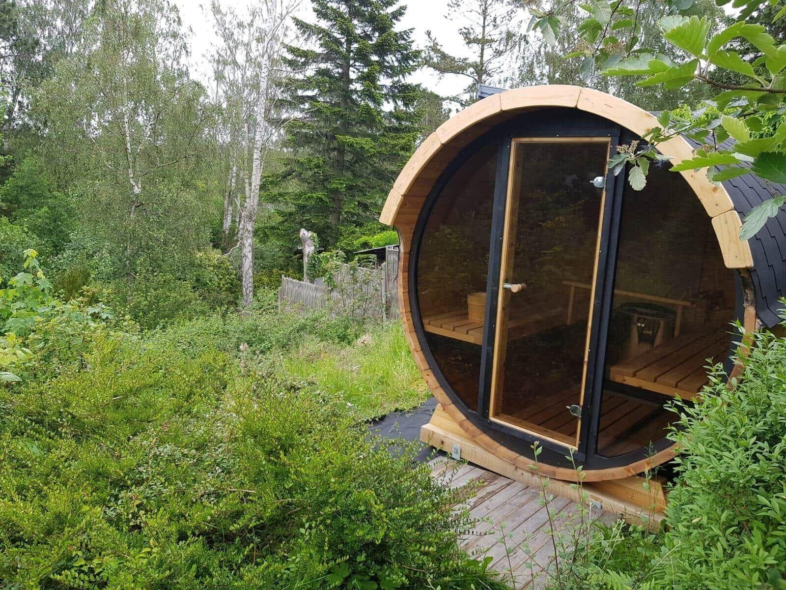 Holzsauna im Wald mit Sitzbänken und Glasfront