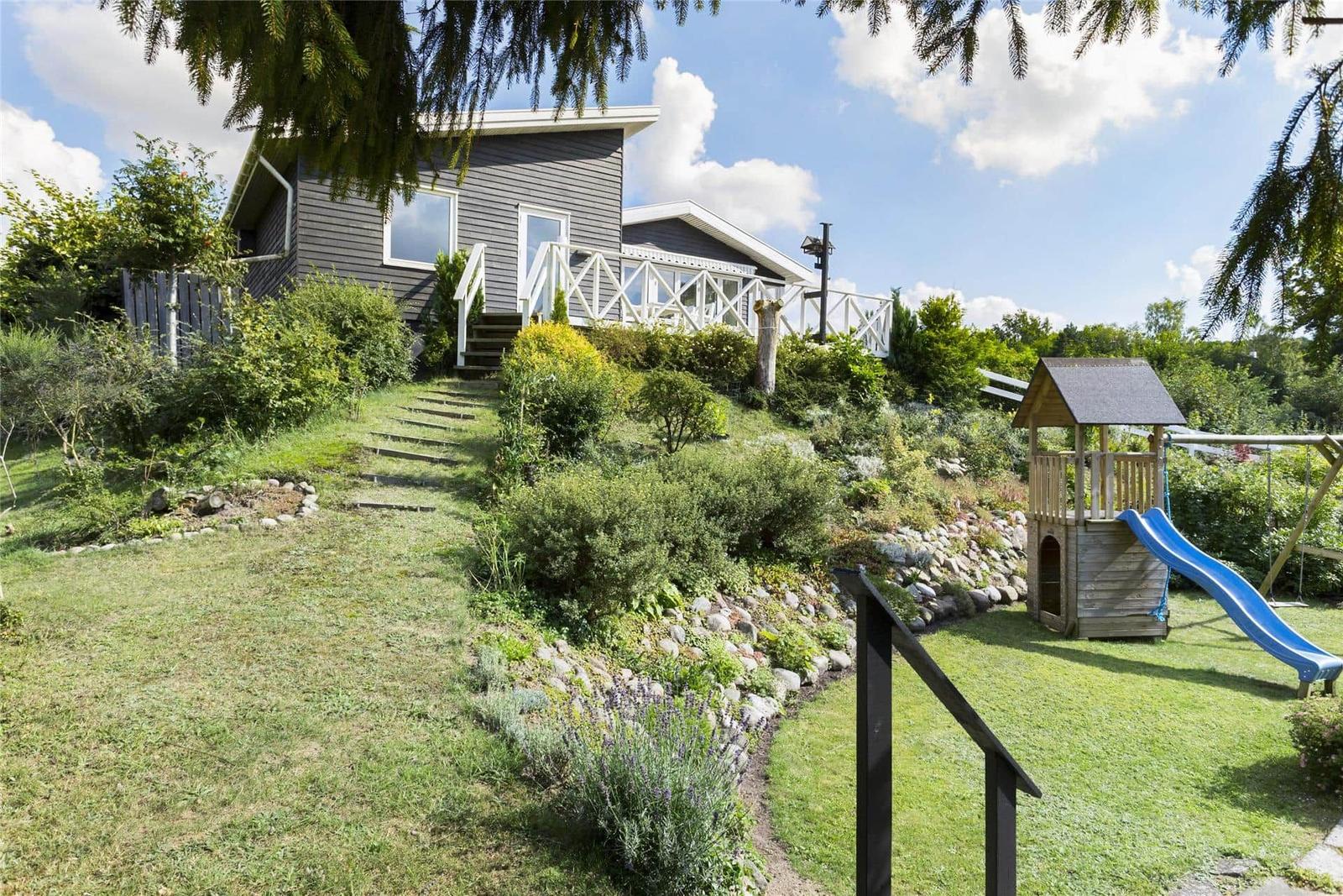 Haus mit Garten, Spielplatz und Treppen zur Terrasse.