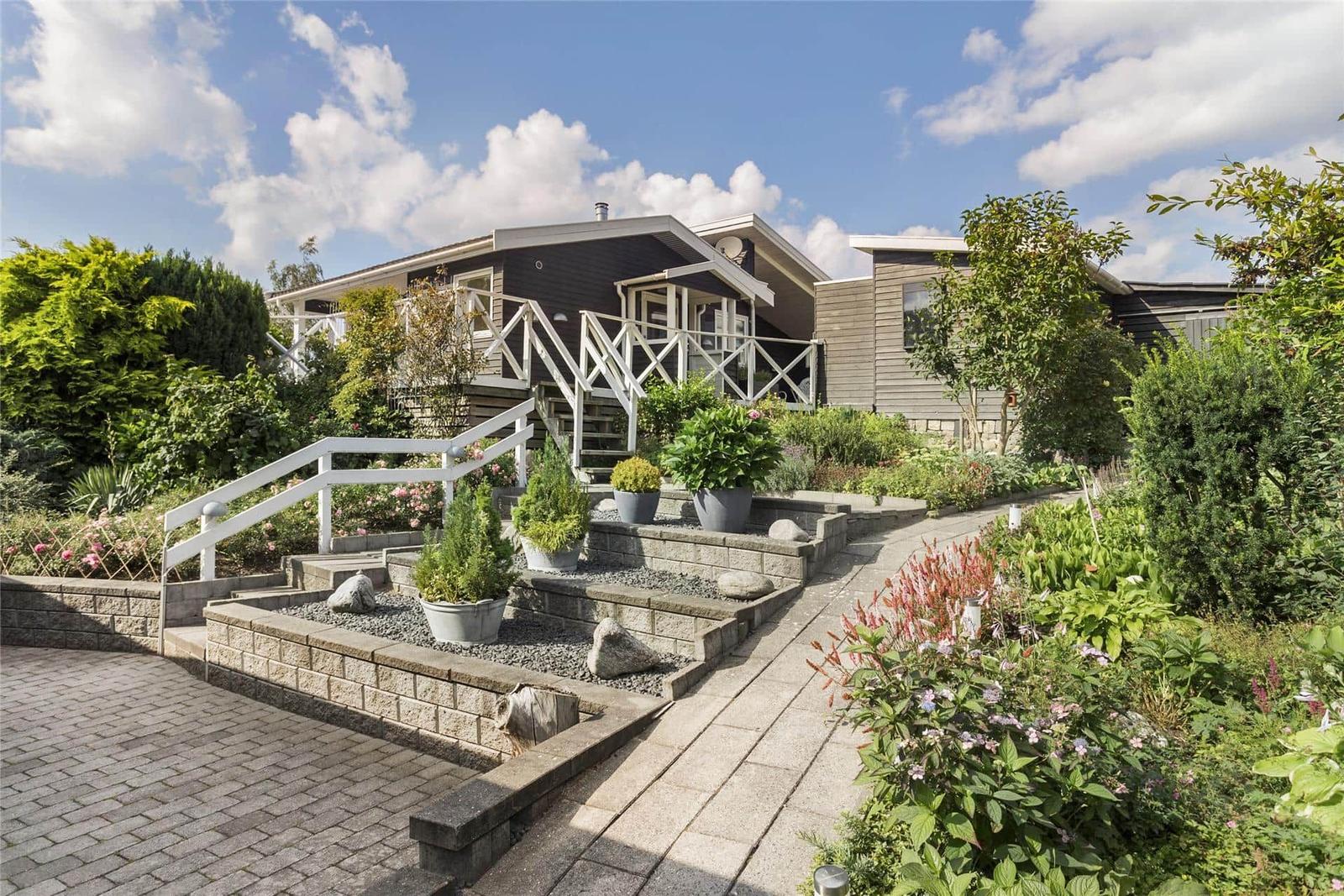 Haus mit Terrasse und gepflegtem Garten unter blauem Himmel.