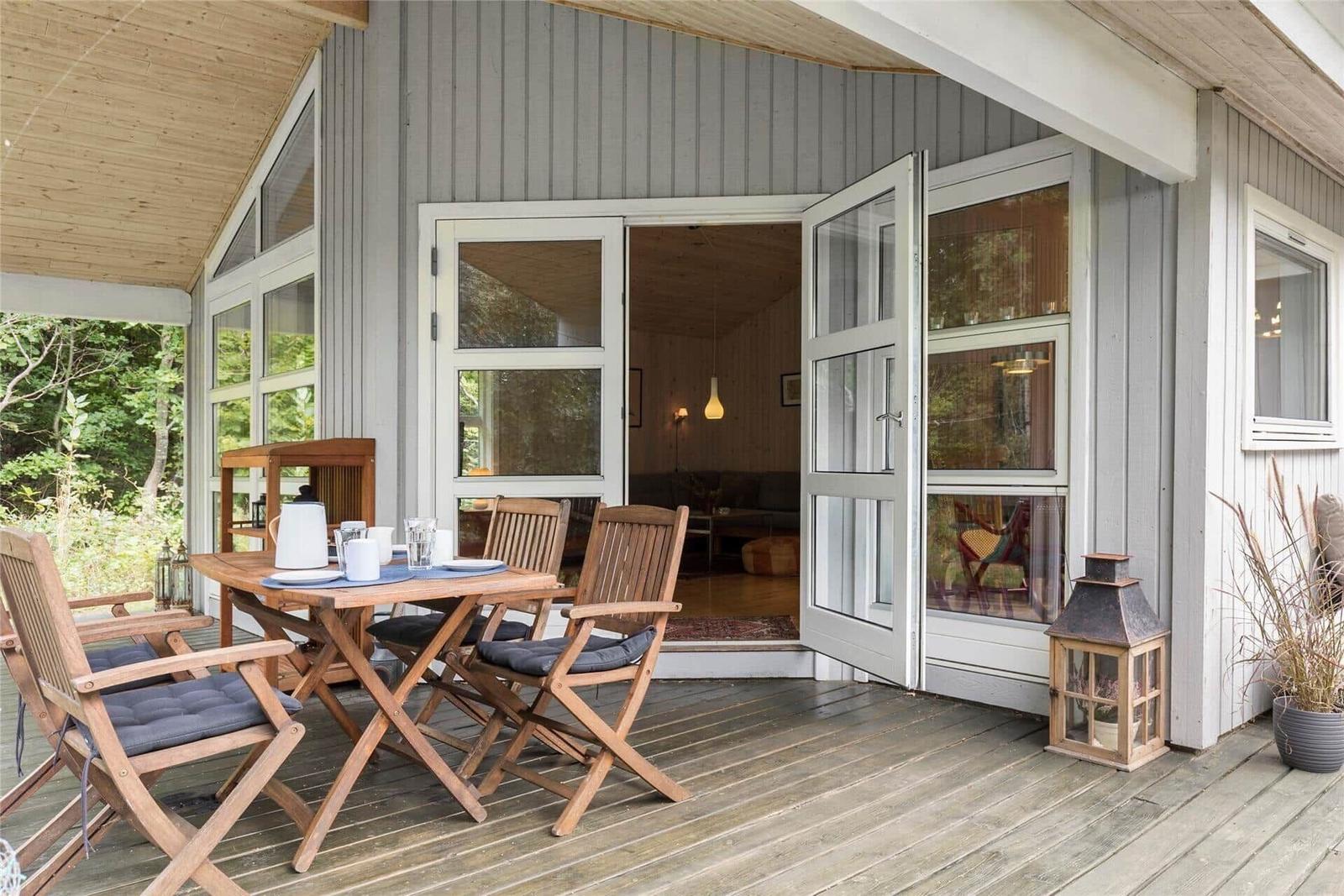 Deck with wooden table and chairs, open door to interior.