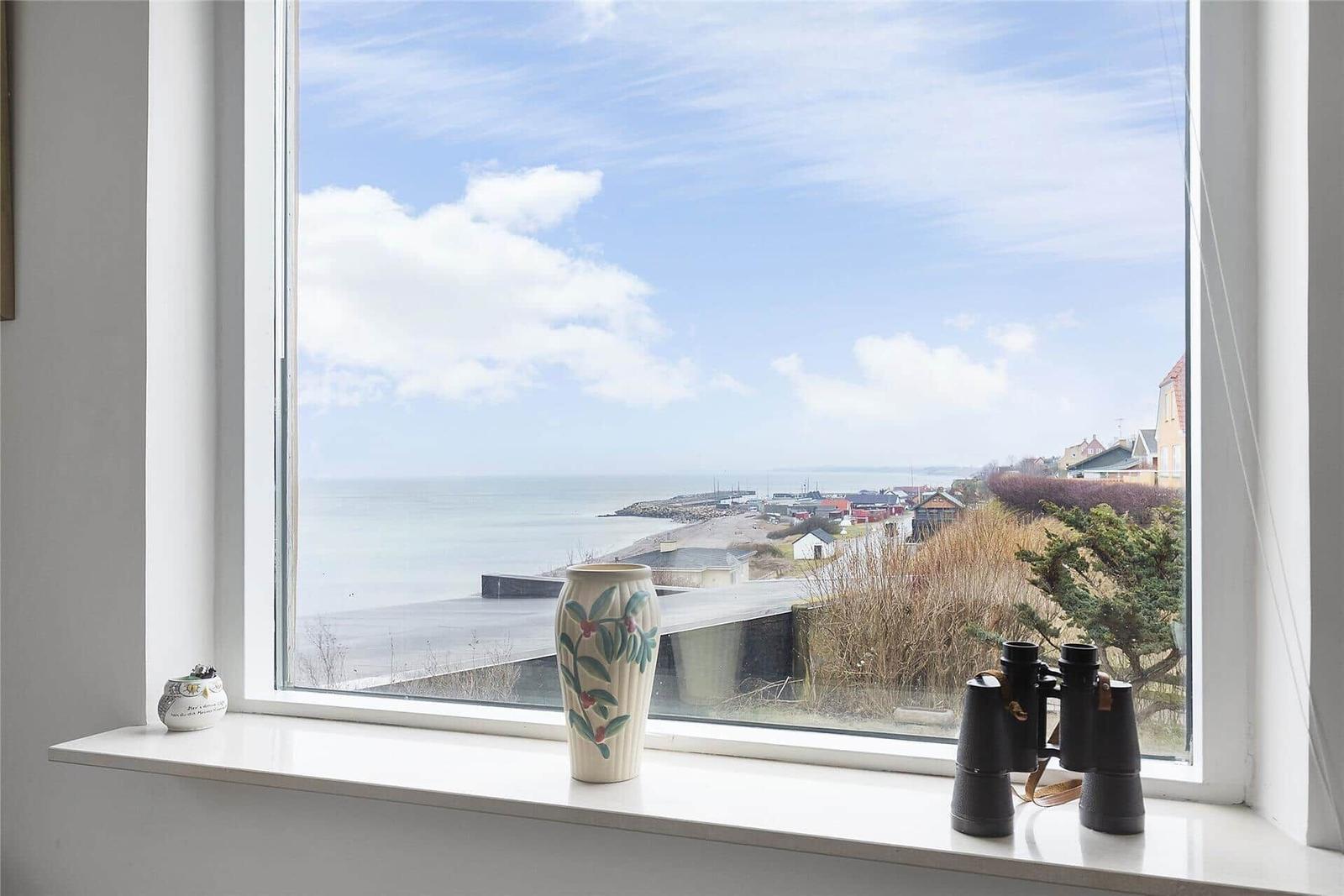 Gelbes Haus mit rotem Dach auf grünem Grundstück mit Blick aufs Meer.