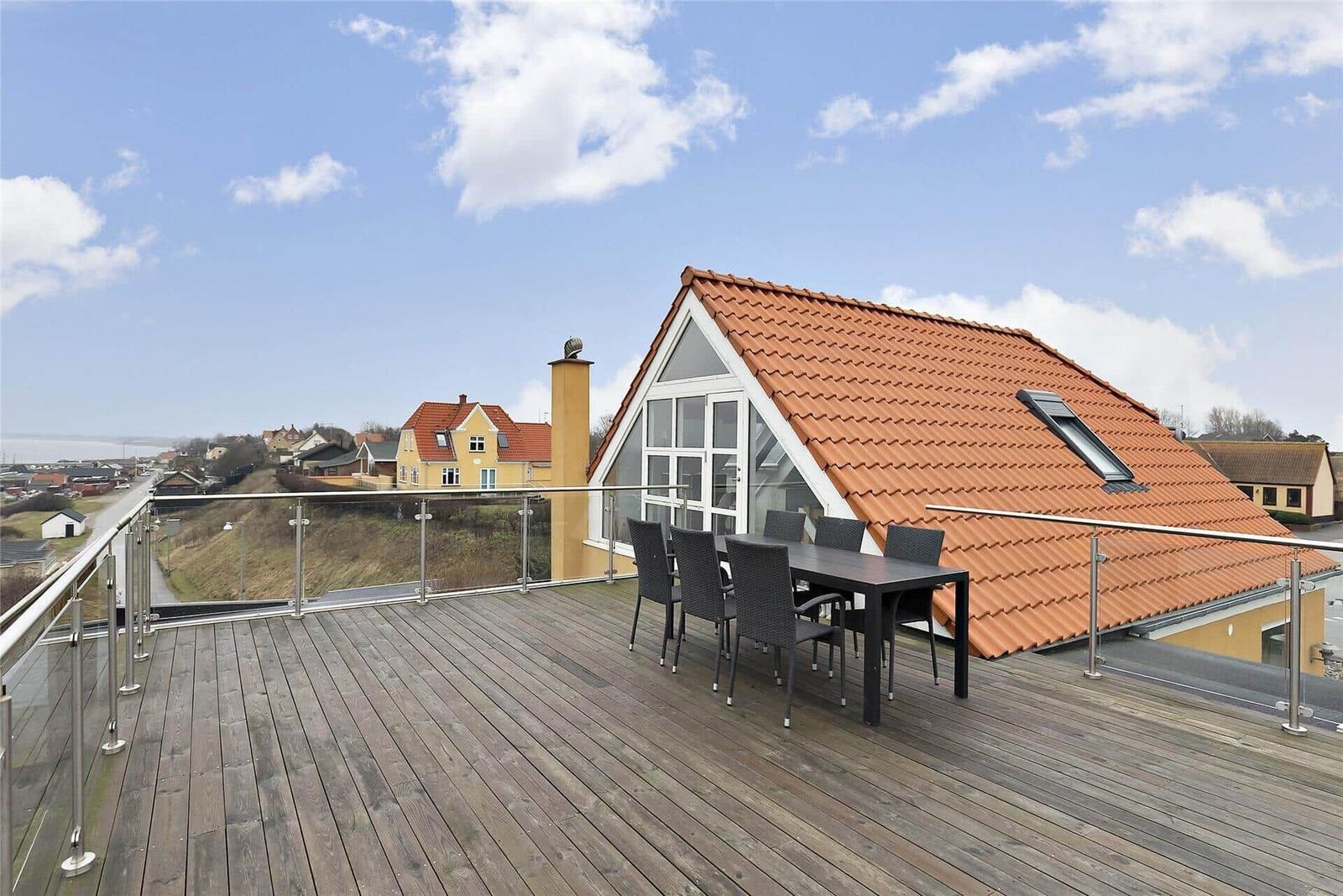 Terrasse mit Tisch, Stühlen und Liegestühlen. Blick auf das Meer und Küstenlandschaft.
