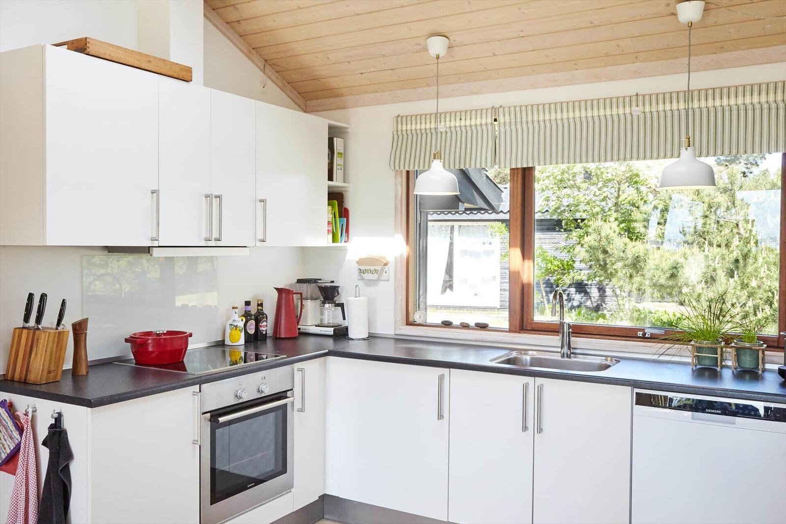 Schlafzimmer mit Holzwand, Bett, Fenster und Kunstwerken an den Wänden.