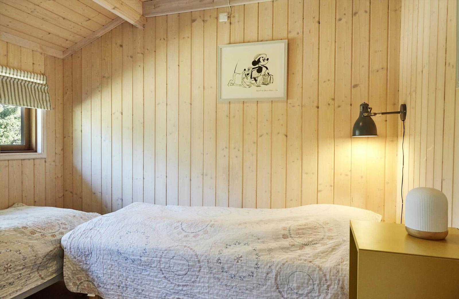 Badezimmer mit Holzwand, Waschbecken, Spiegel und Dusche.