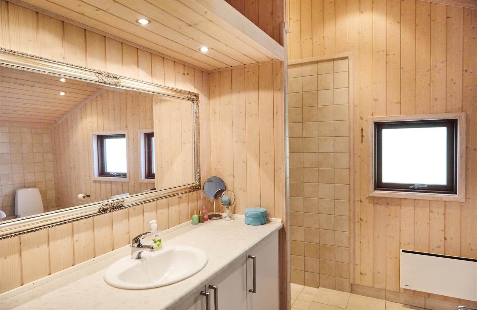 Bad mit Dusche, Waschbecken und Spiegel an Holzwand