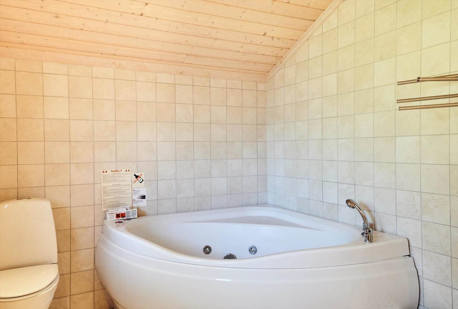 Bad mit Waschbecken, Spiegel und Handtuch an der Wand.