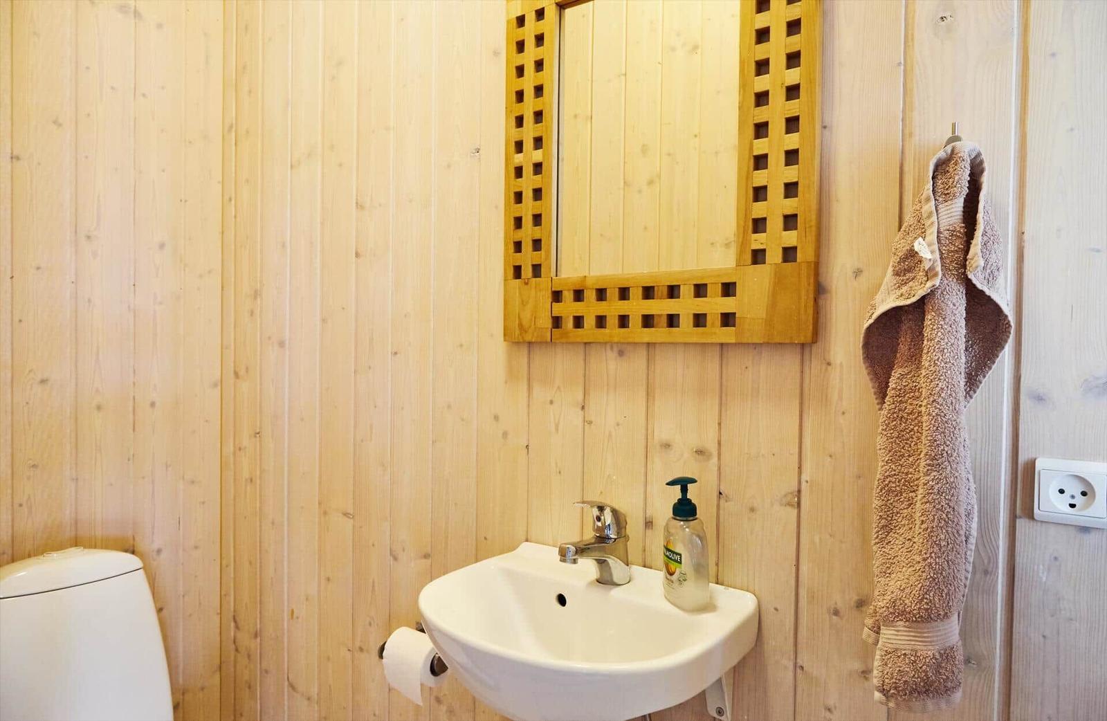 Schlafzimmer mit Holzwand, Bett, Kleiderschrank und Fenster zum Garten.