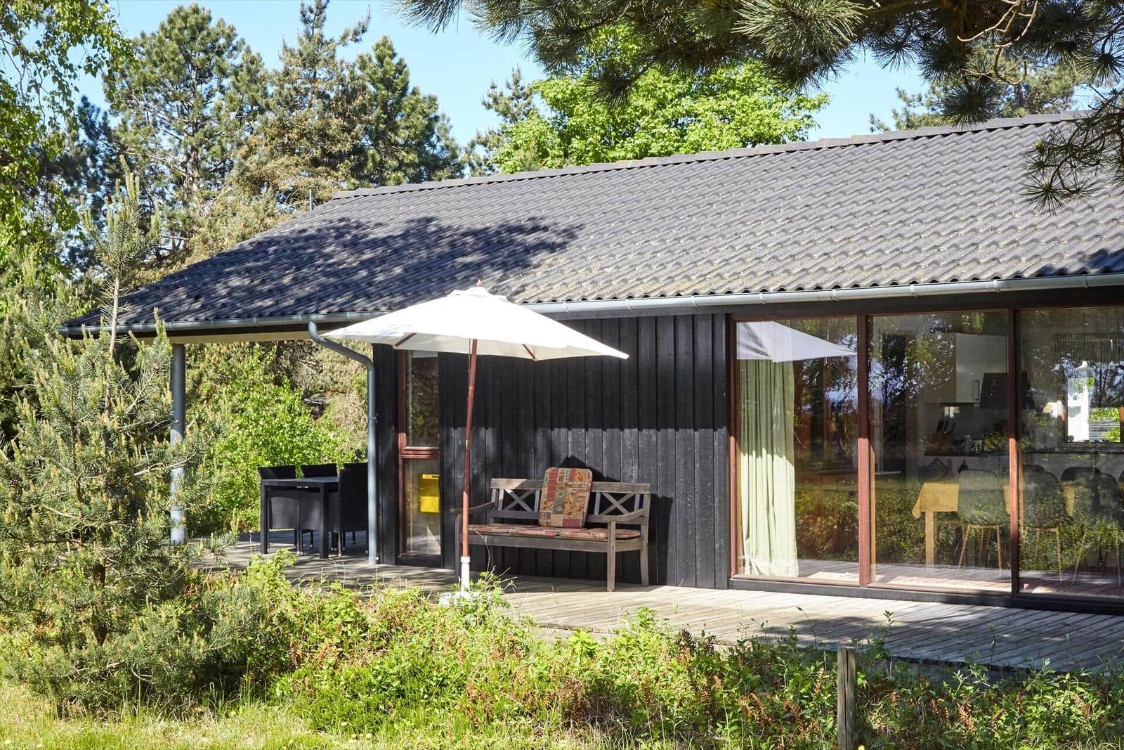 Terrasse mit Bank, Sonnenschirm und Blick in den Garten.
