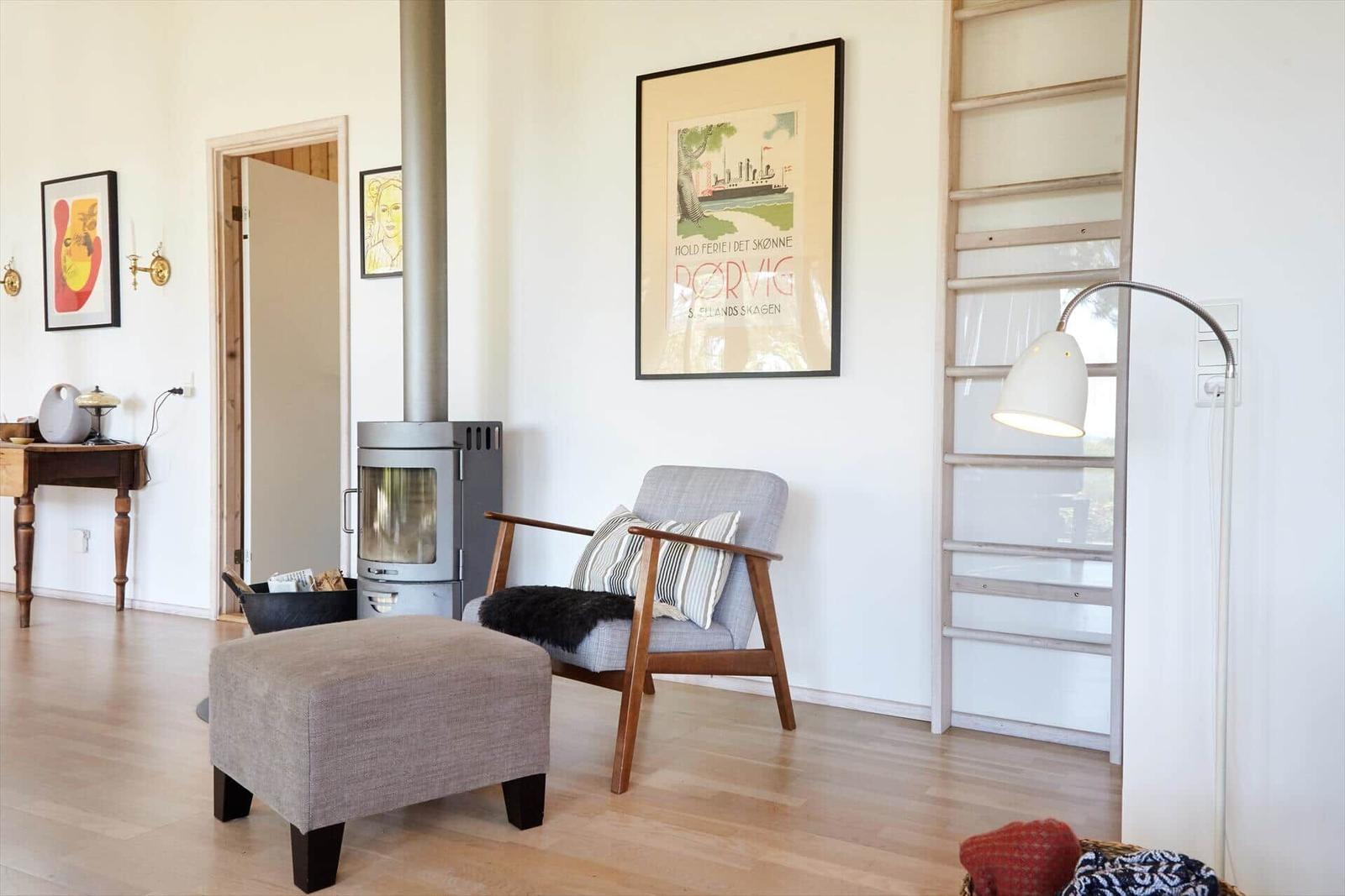 Wohnzimmer mit Ecksofa, Holztisch und Wandbildern. Decke mit Holzverkleidung und großes Fenster.