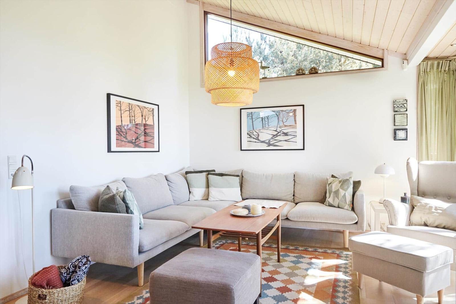 Wohnzimmer mit Sofa, Sessel und großem Fensterblick auf Garten.