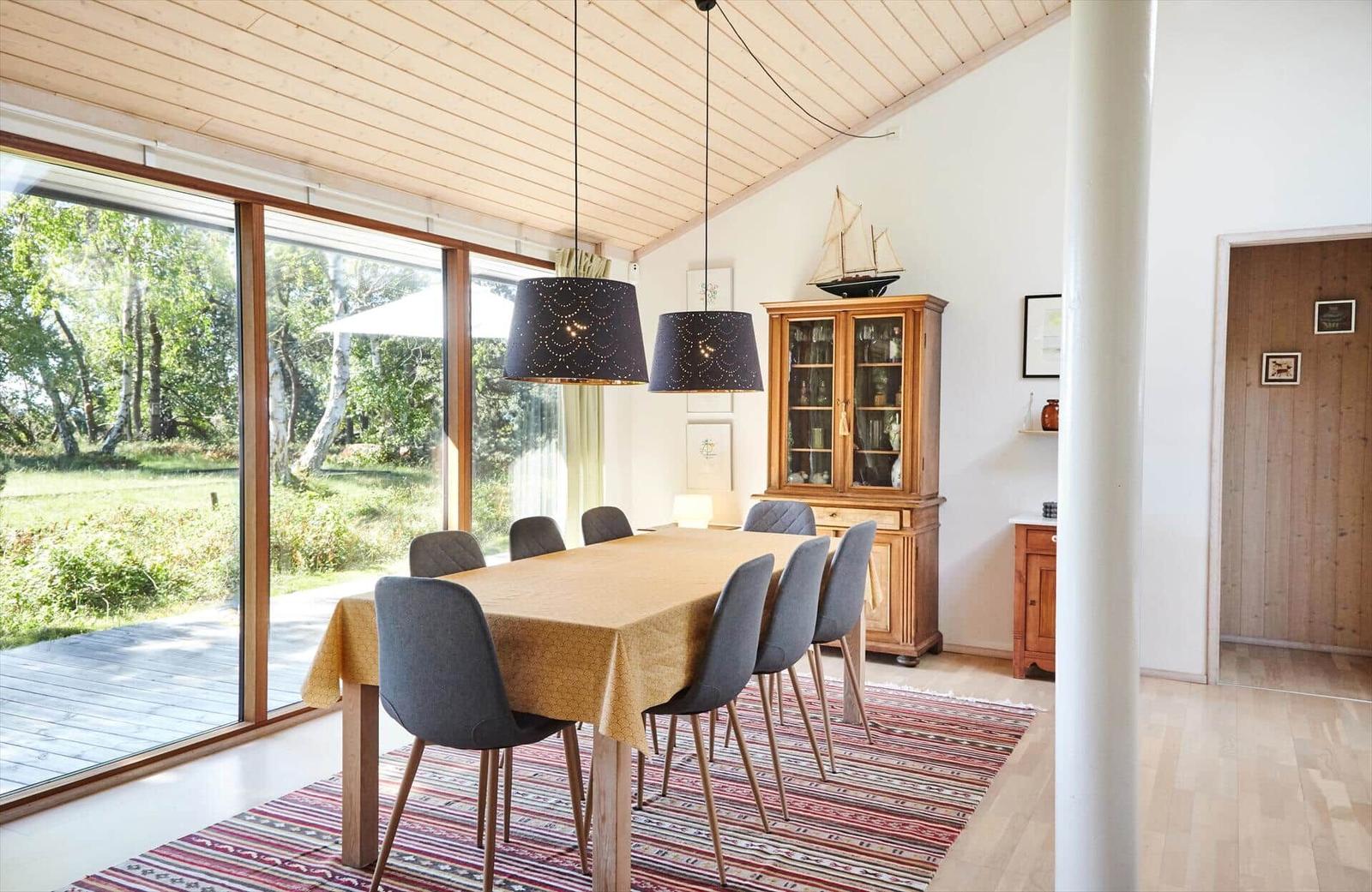 Essbereich mit Tisch, Stühlen und Küchenbereich im Hintergrund.