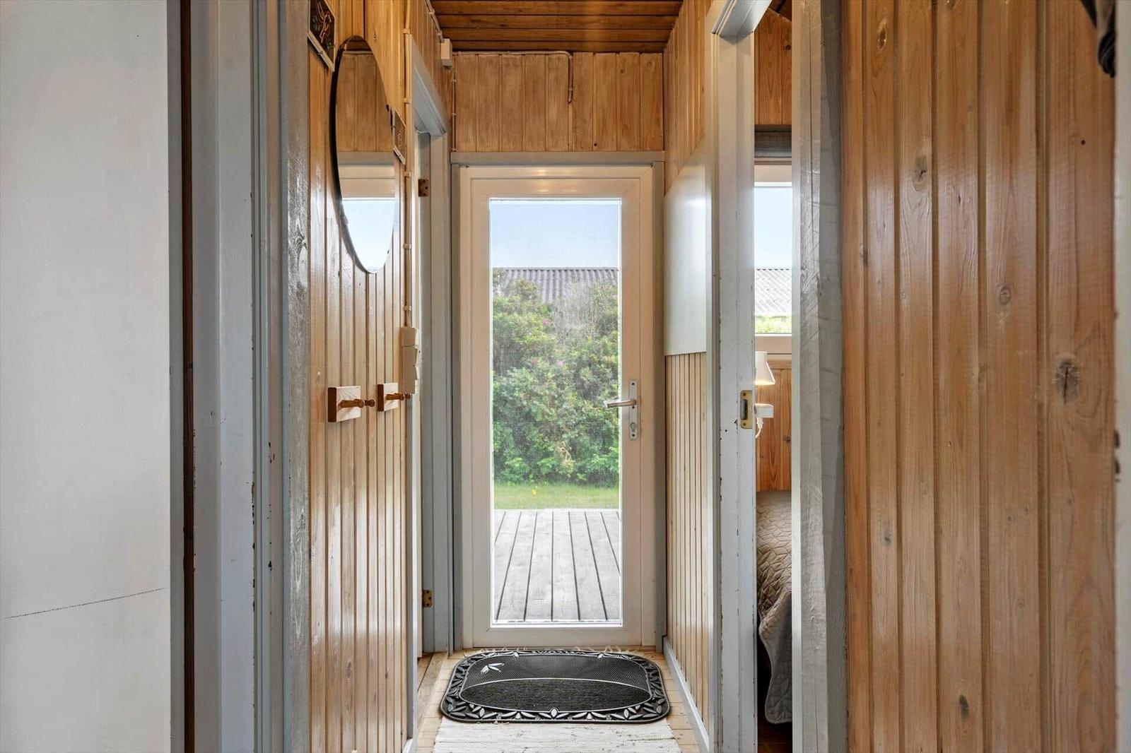 Schlafzimmer mit Holzwand, Bett, Schränken und Fenster unter Dachschräge.