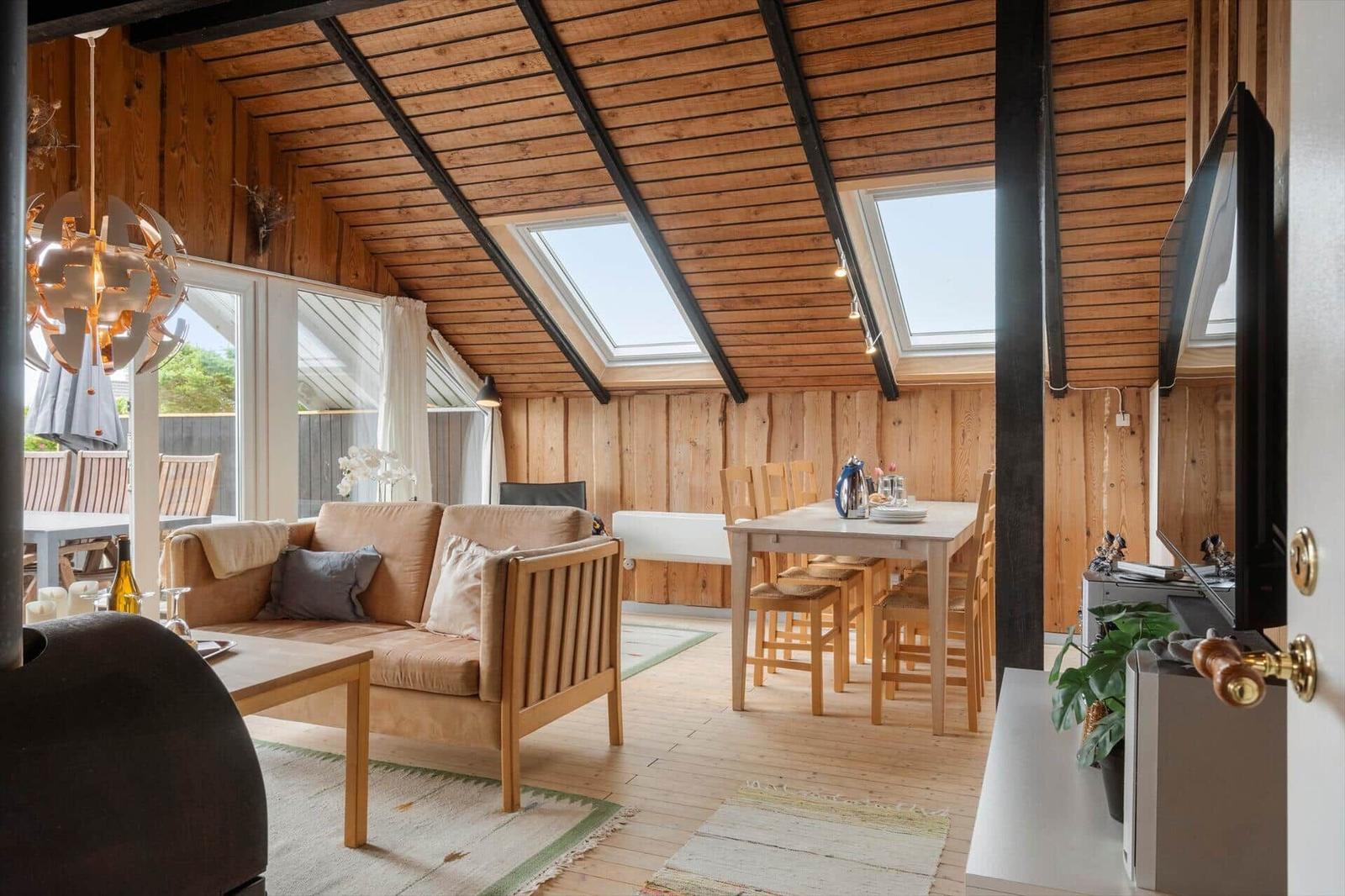 Haus mit Terrasse, Garten und Schaukel. Weiße Bank und Stühle auf Holzterrasse.