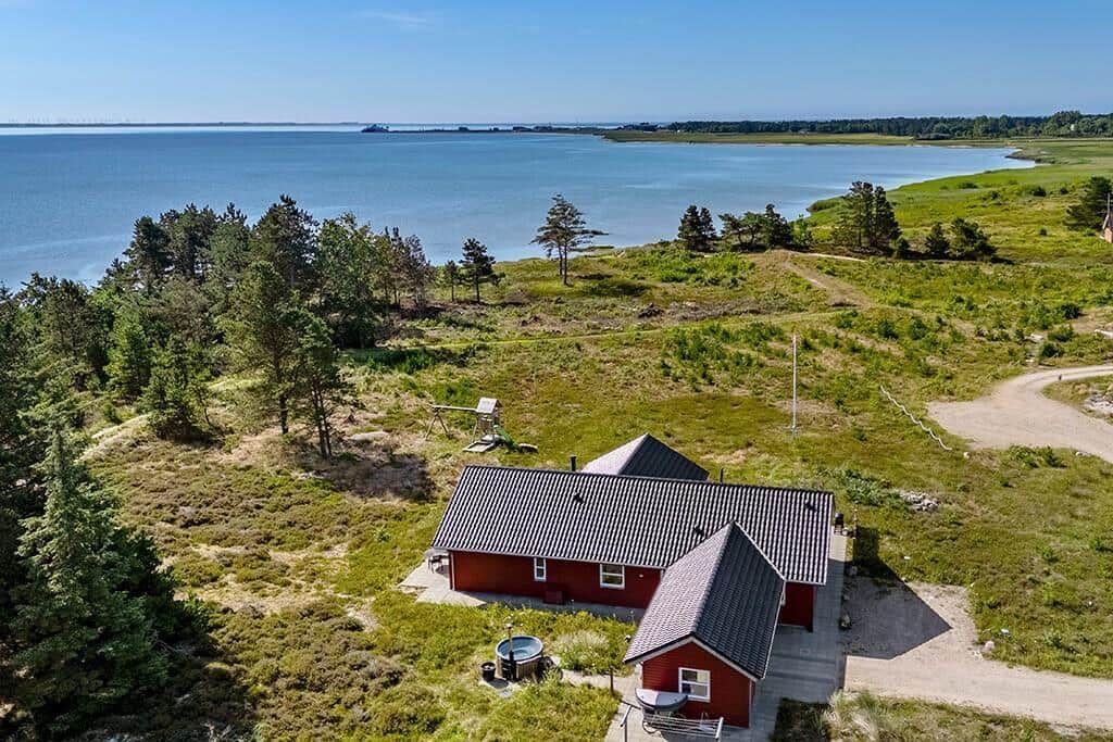 Rotes Haus mit Terrasse, umgeben von Wald und Meer.