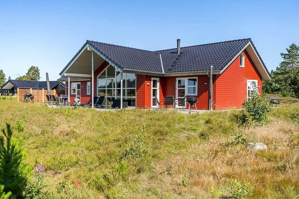 Rotes Haus mit großem Garten und Wald im Hintergrund.