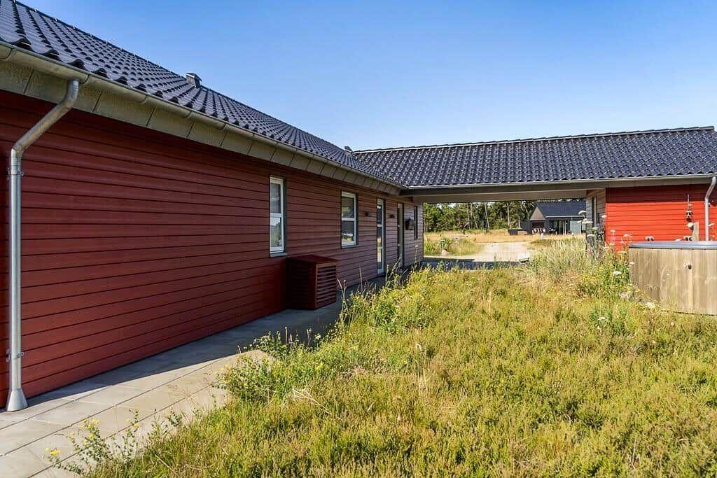 Grünes Gelände mit Spielplatz und Grill im Vordergrund. Im Hintergrund sind Bäume und Wasser sichtbar.