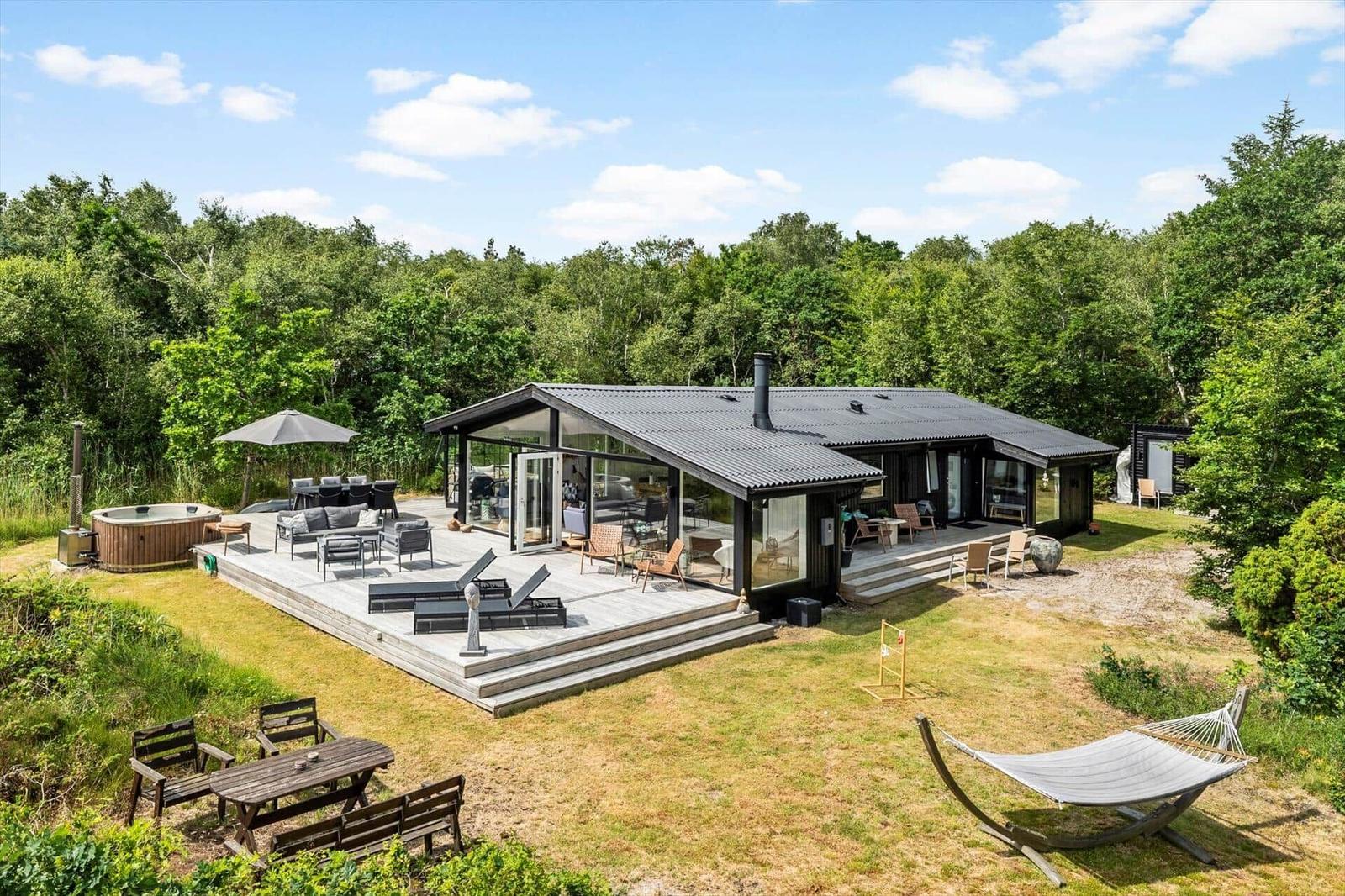 Terrasse mit Tisch, Stühlen, Sonnenschutz und Glasgartenhaus. Grill und Pflanzen sind vorhanden.