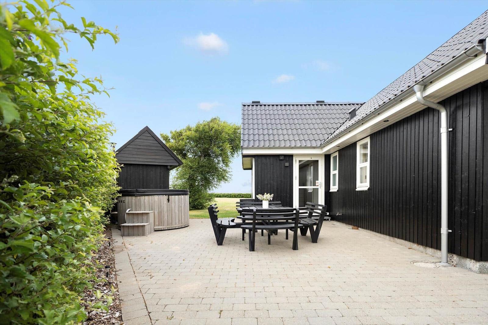Schwarzes Haus mit Terrasse, Garten und Aussicht auf Felder.