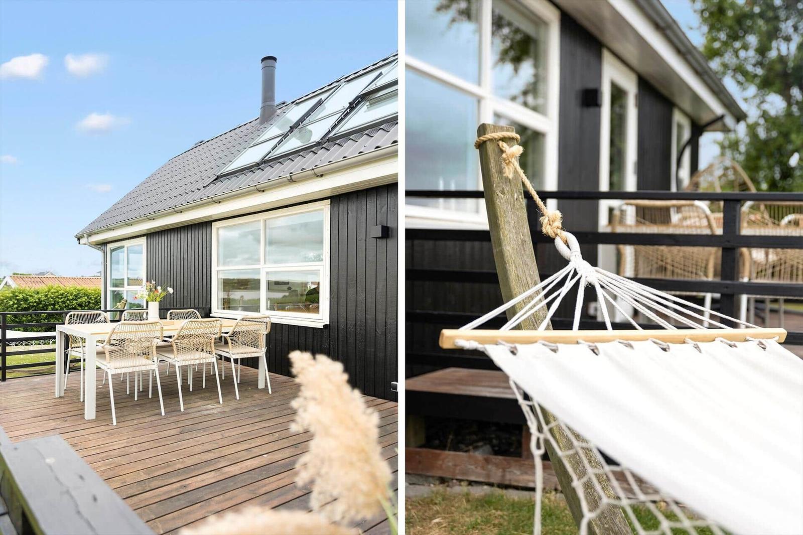 Schwarzes Haus mit Terrasse, umgeben von Grün und Blick auf das Meer.
