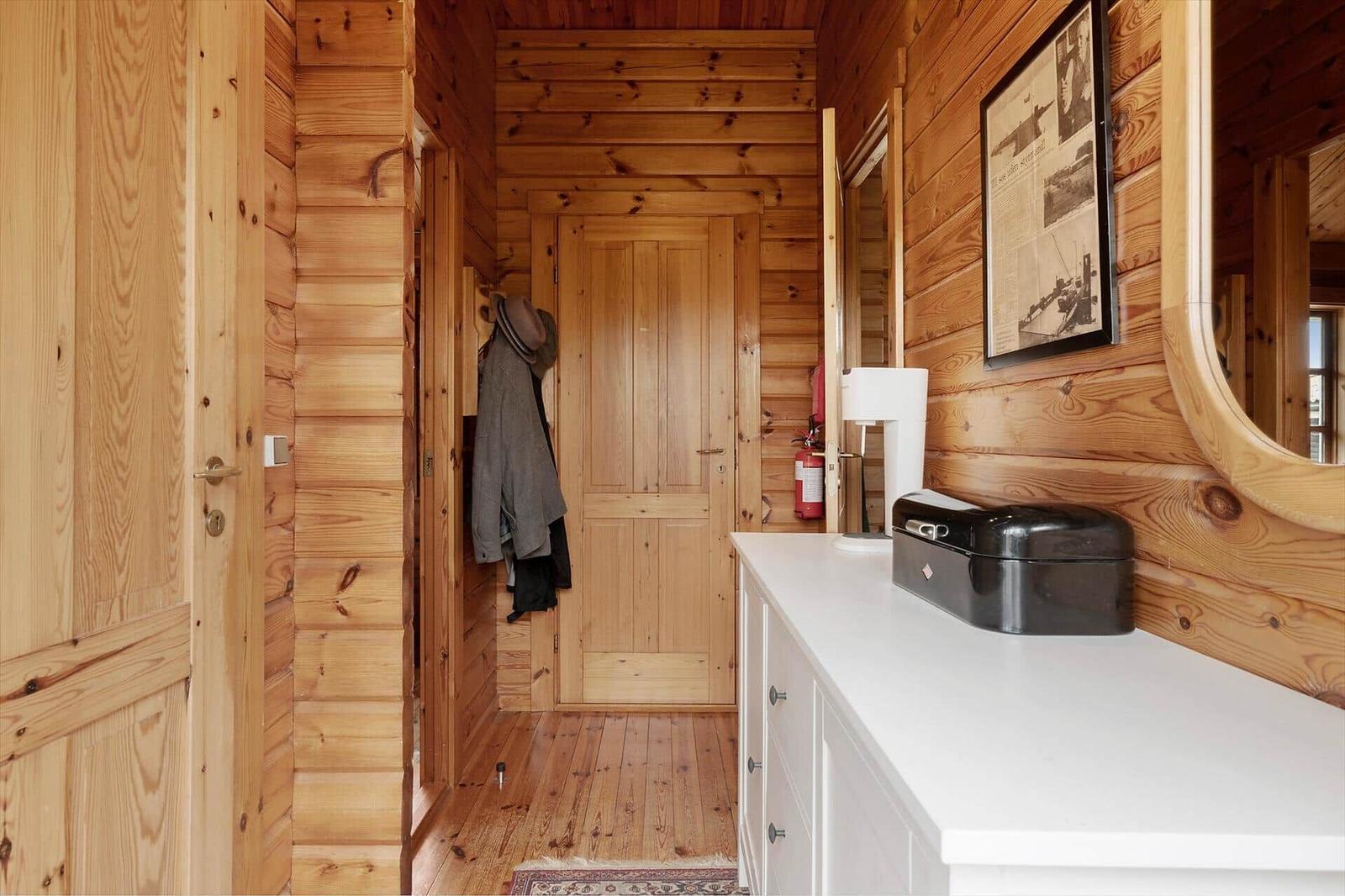 Wooden wall with desk, bookshelf, and lamp. Wood-burning stove with fire.