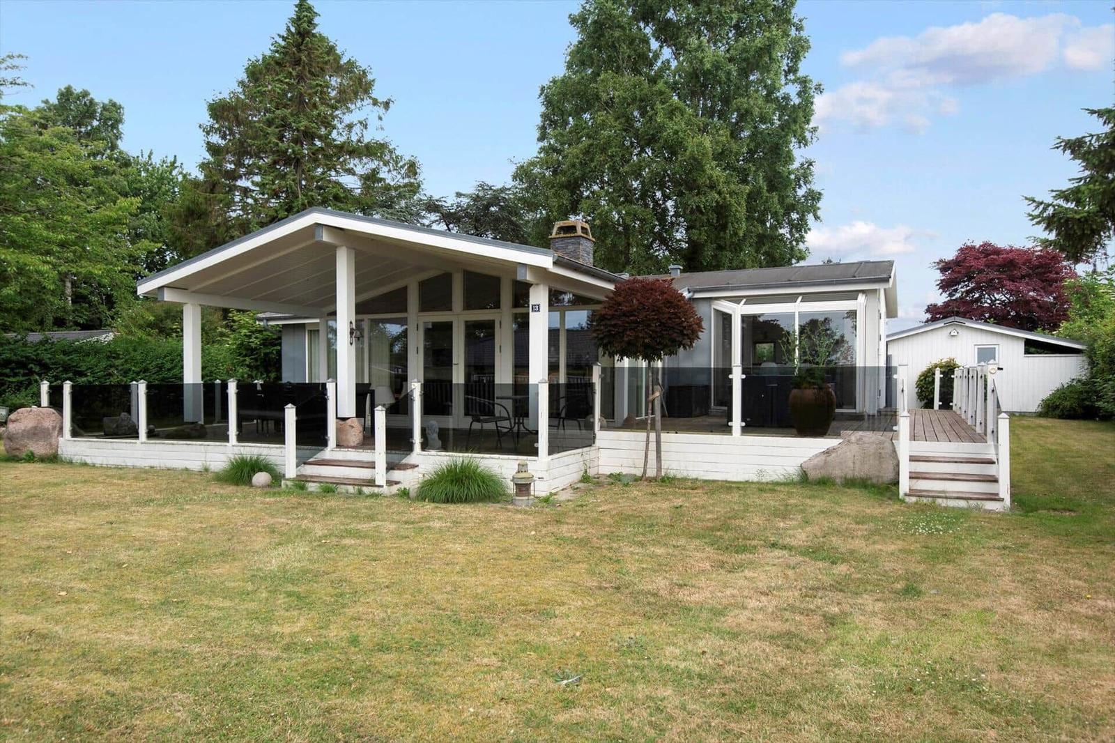Terrasse mit Sitzgruppe, Glasgeländer und Blick auf grüne Hedges.