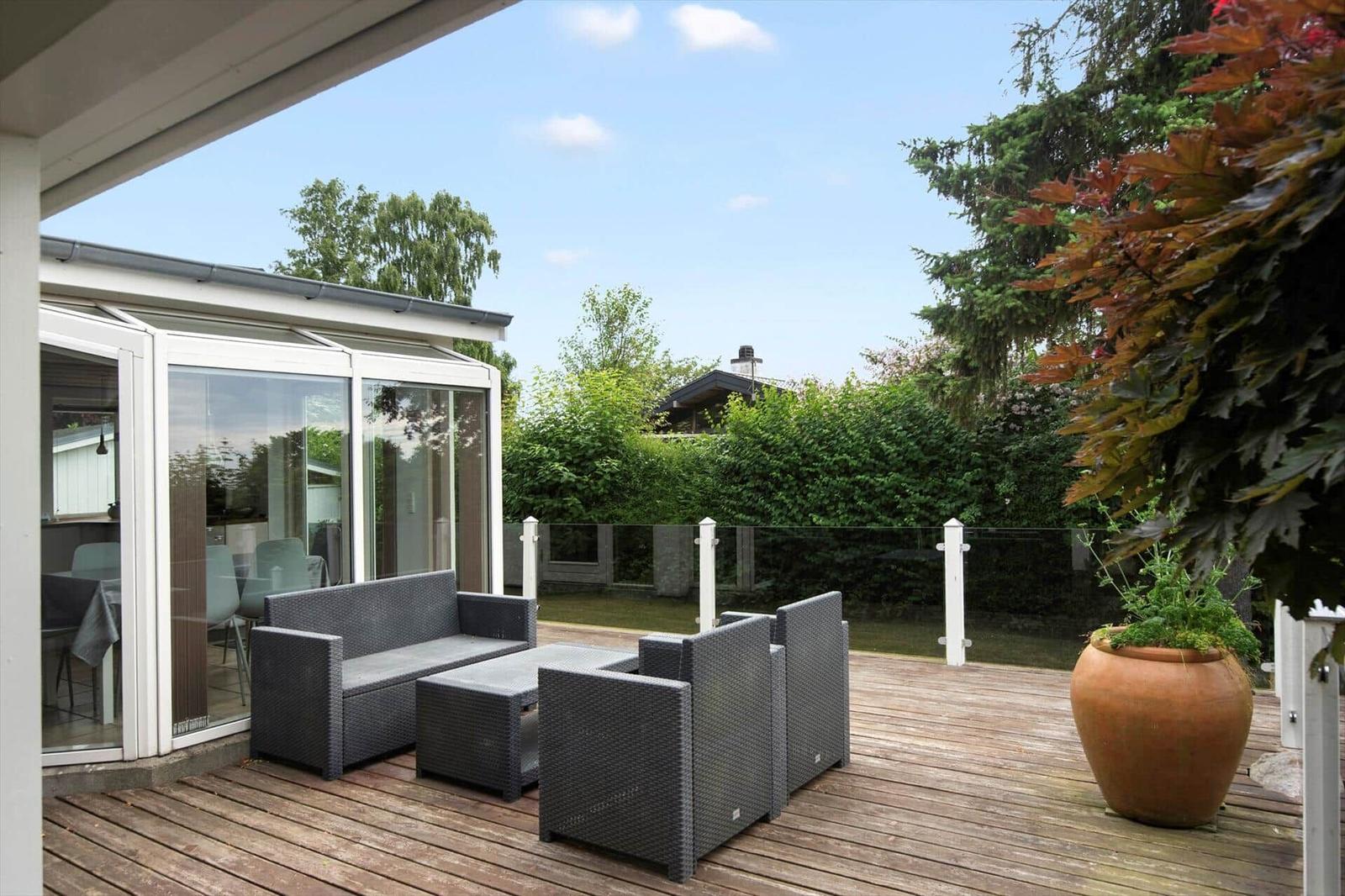 Terrasse mit Sitzgelegenheiten und Blick auf Garten und Bäume.
