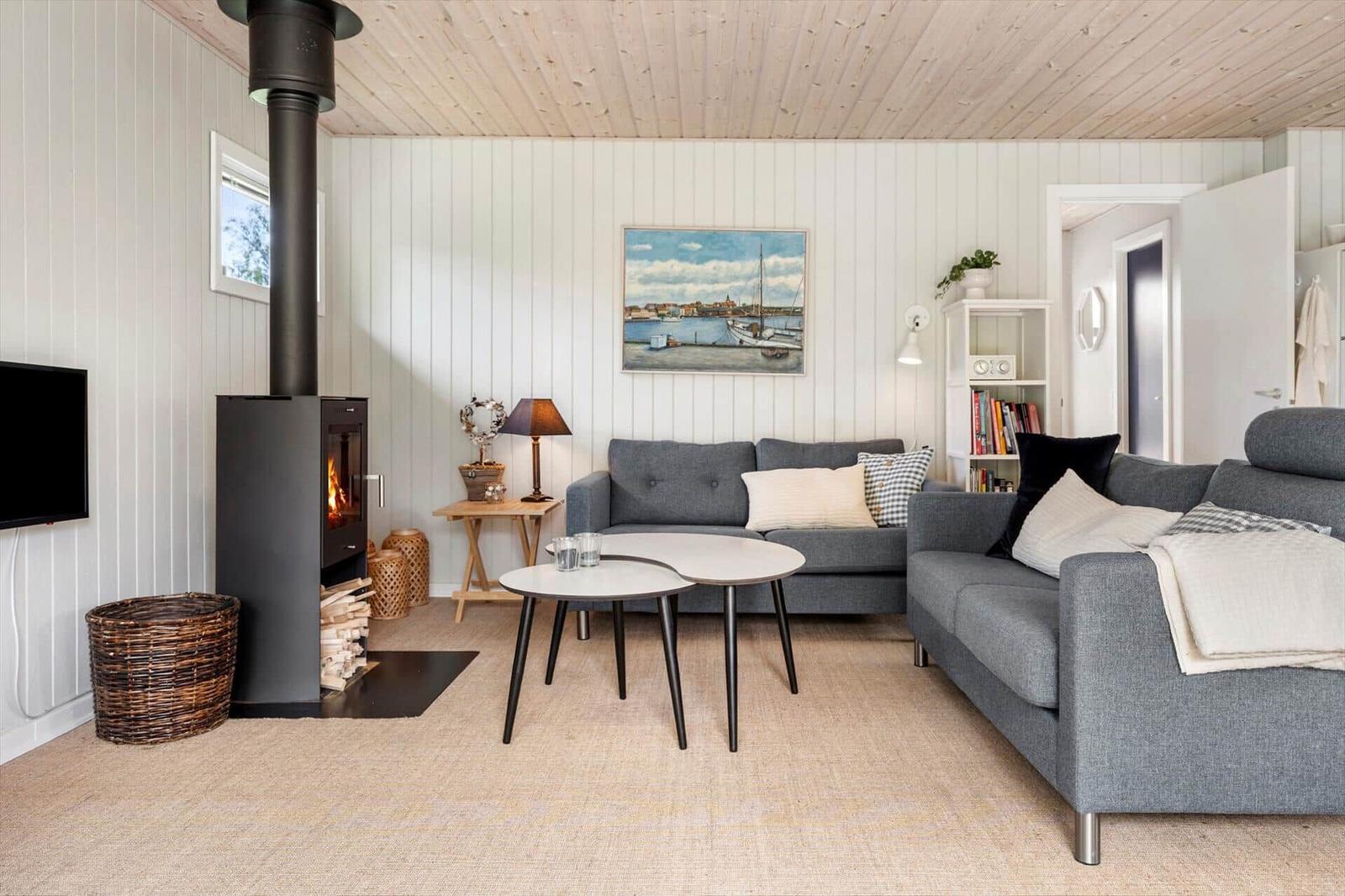 Living room with fireplace, sofa, and table. Wall painting and bookshelf visible.