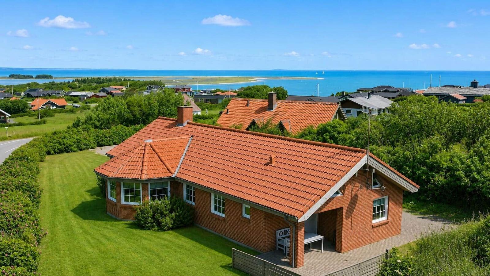 Ein Haus mit rotem Dach und grünem Garten. Blick auf das Meer und die Umgebung.