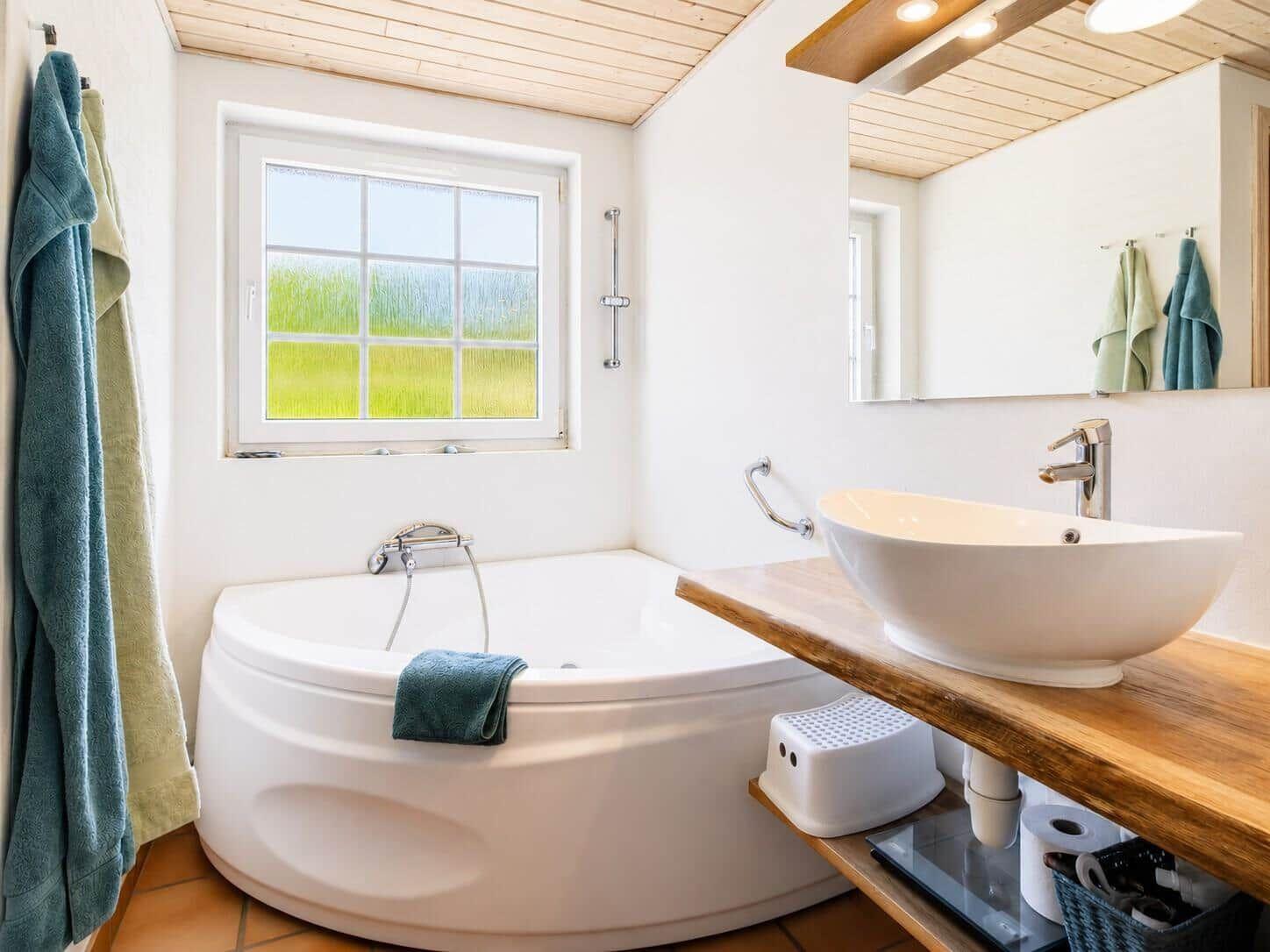Bad mit Badewanne, Waschbecken und Fenster mit Grünblick.