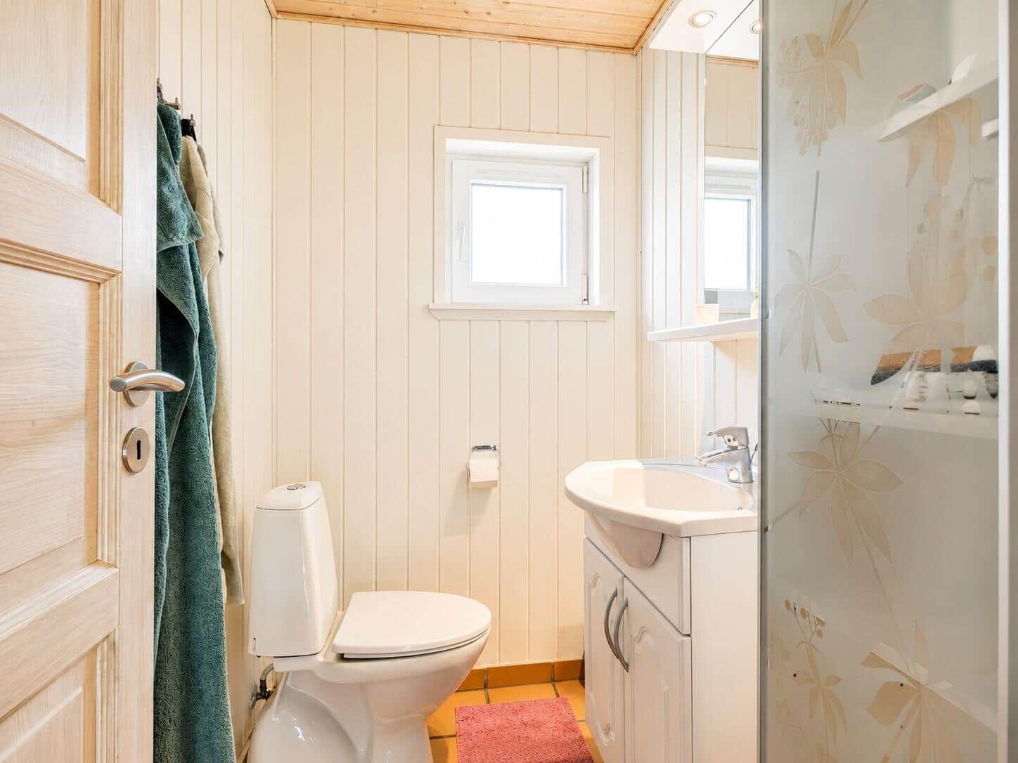 Badezimmer mit Toilette, Waschbecken und Dusche mit Glaswand.