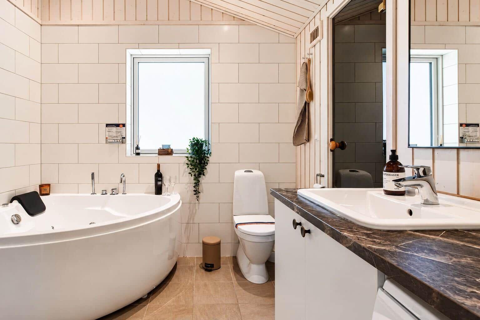 Badezimmer mit Badewanne, Toilette und Waschbecken mit Spiegel.