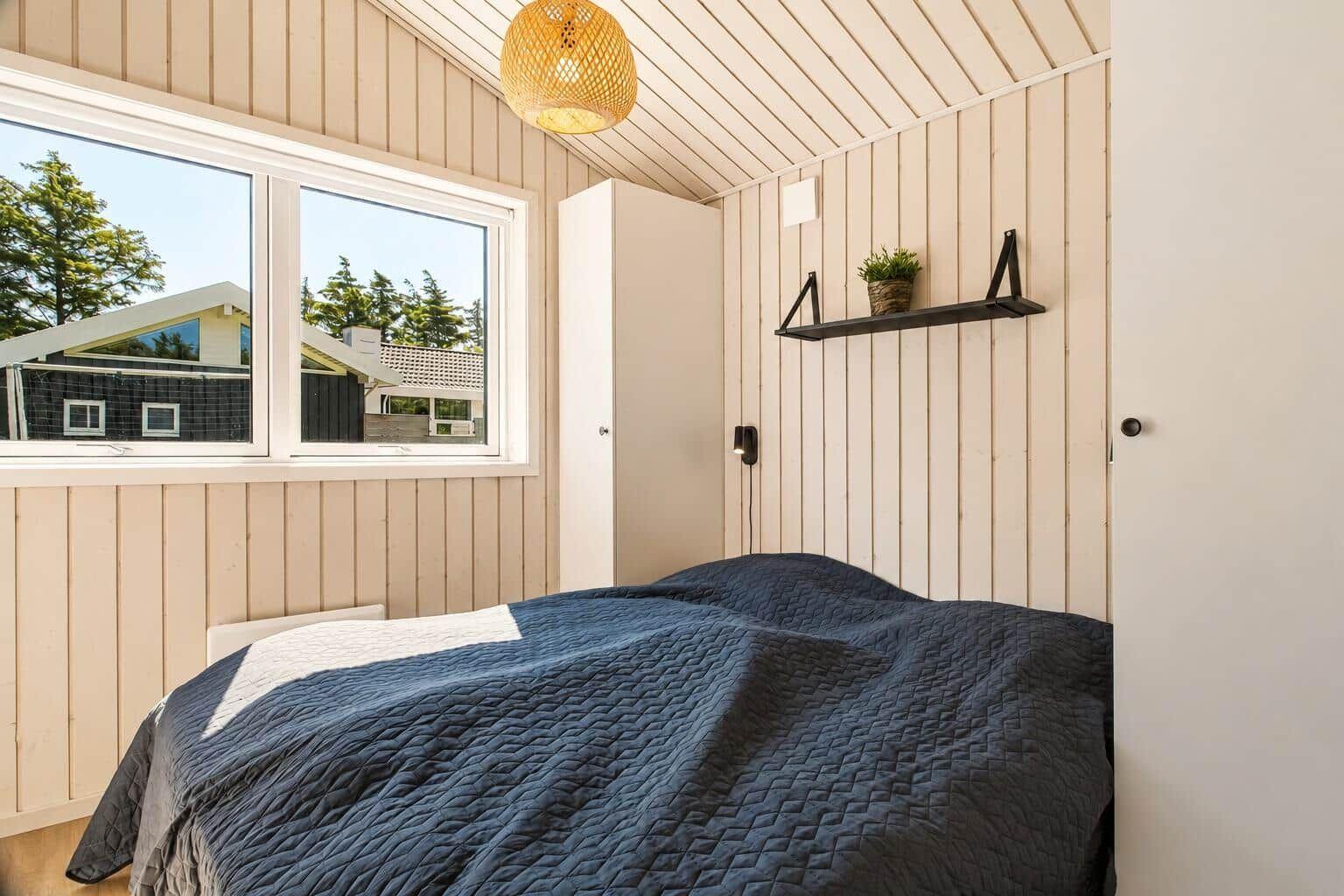 Schlafzimmer mit Bett, Fenster und Schrank an der Wand