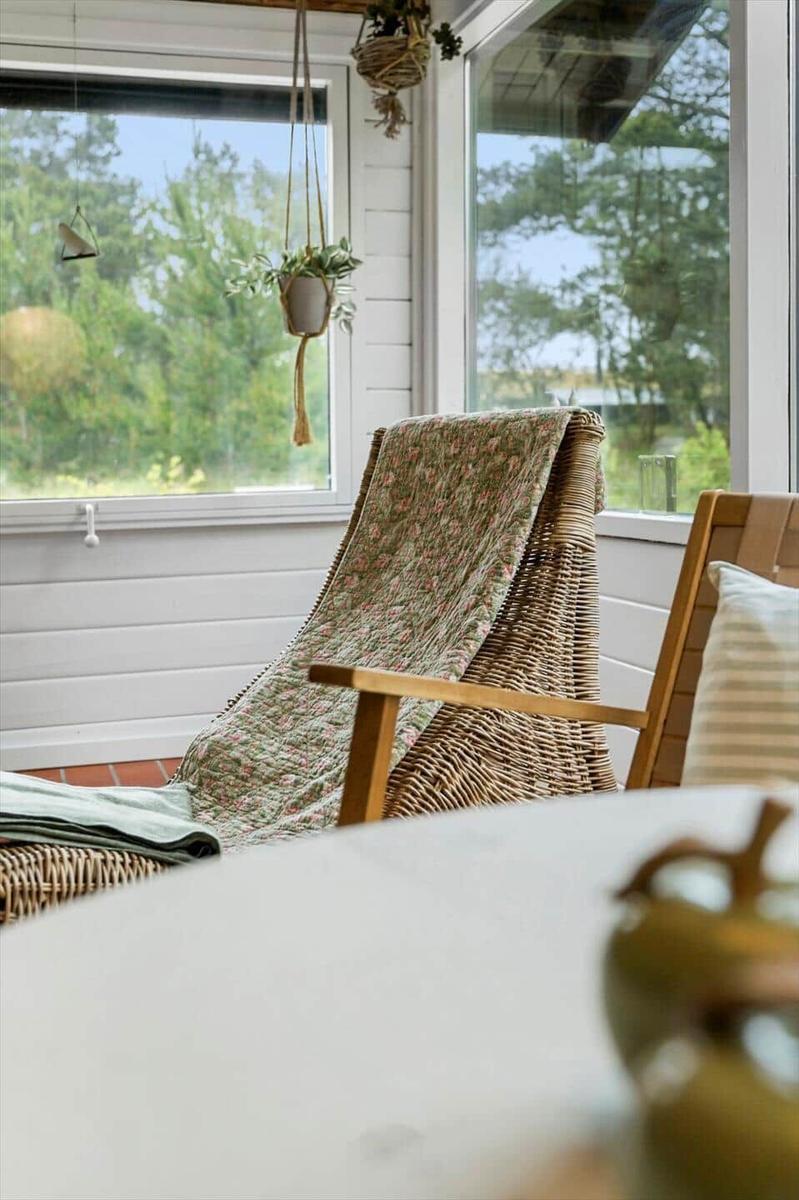 Wohnzimmer mit schwarzer Couch, Holzstühlen und einem runden Tisch auf Teppich.