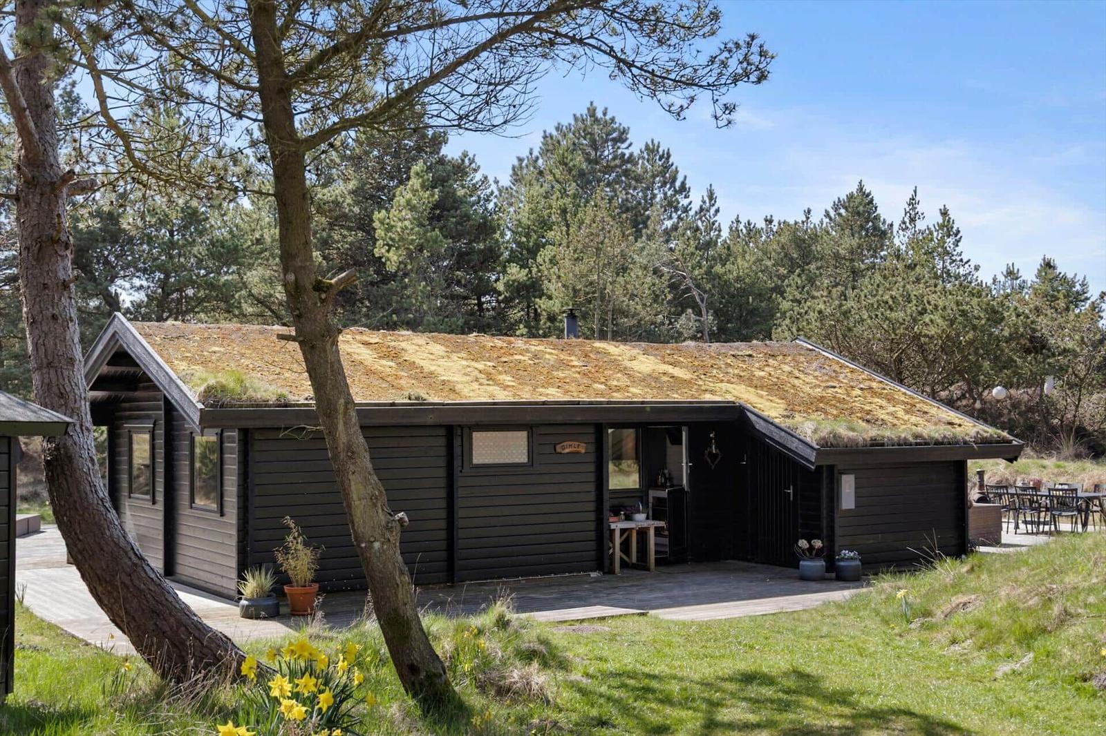 Wohnzimmer mit Holzbalken, Kamin und Sitzgelegenheiten auf Terrakottaboden.