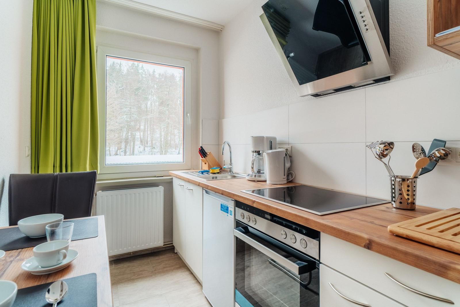 Küche mit Holz Arbeitsplatte, Herd und Fenster zum Wald.